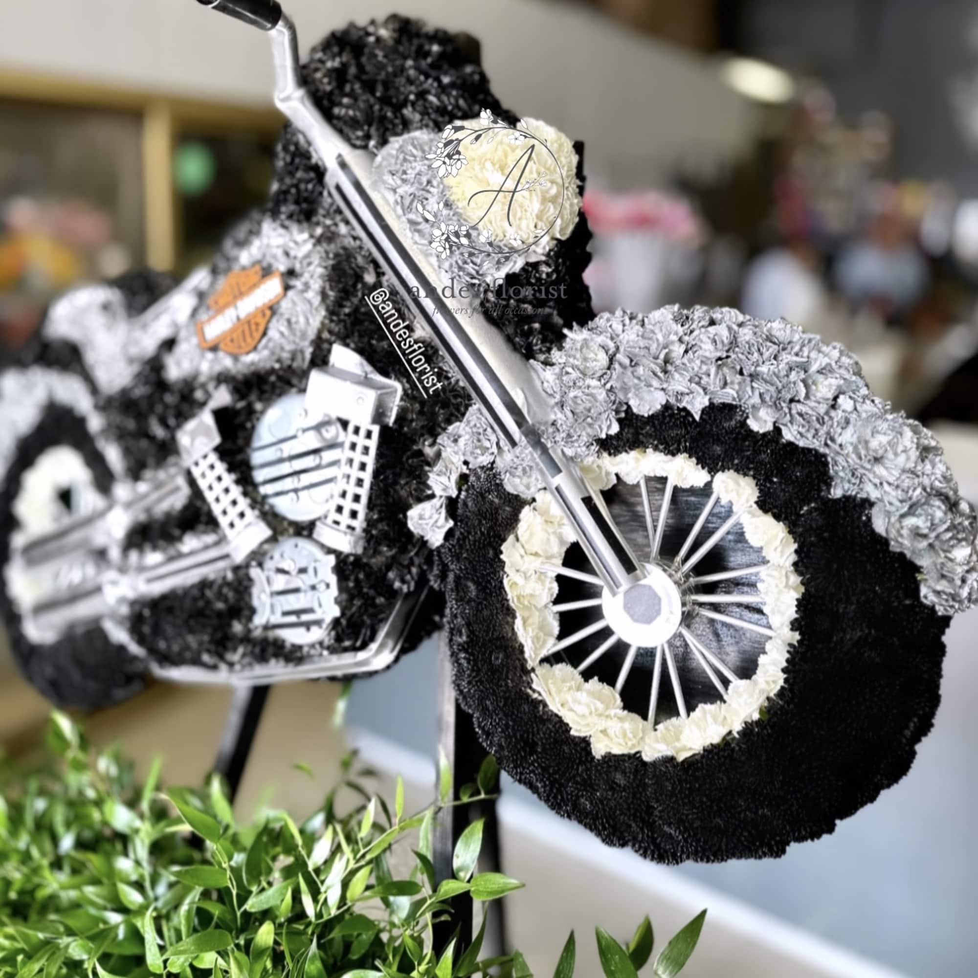 Motorcycle-shaped floral tribute with black and white flowers
