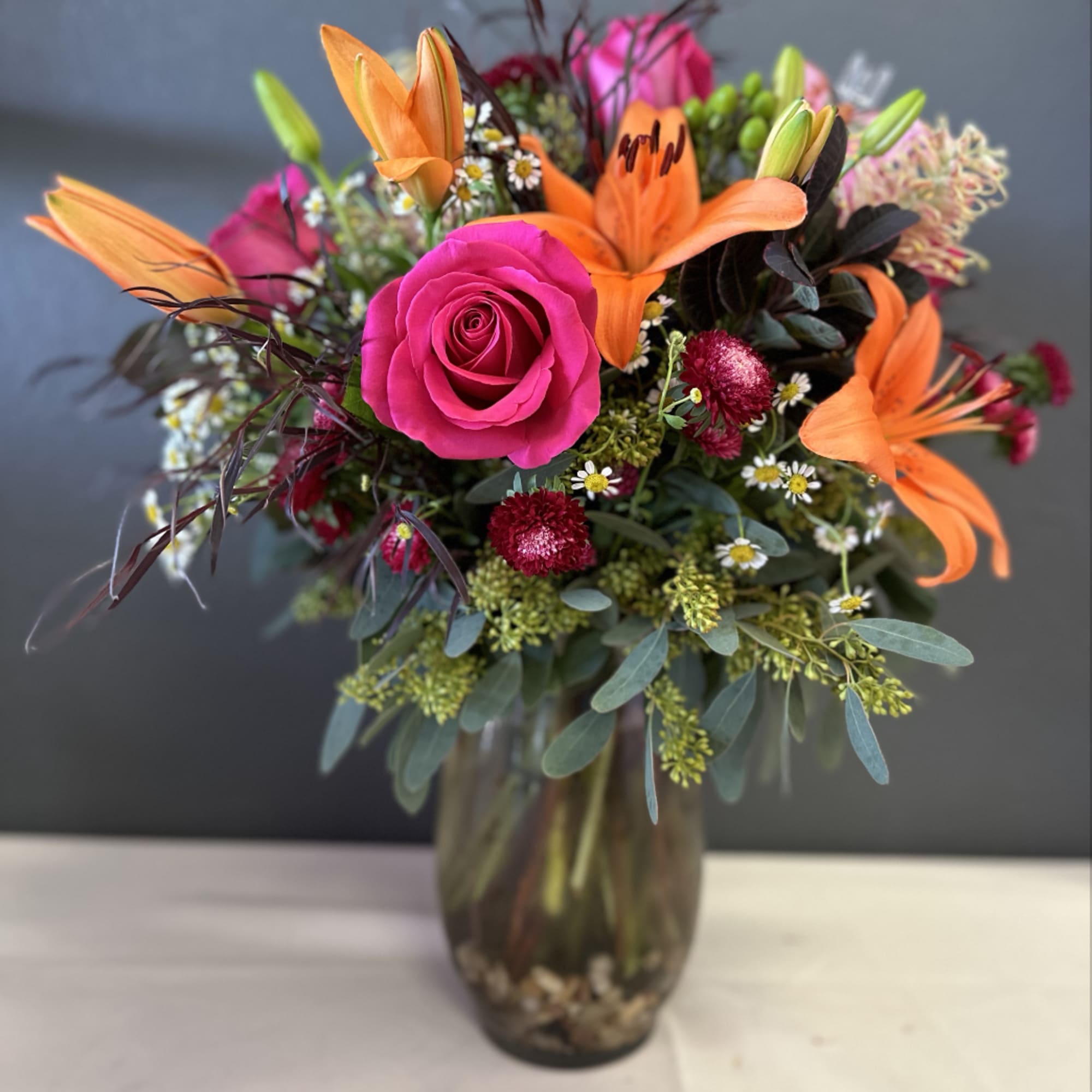 Bright mixed bouquet with pink roses and orange lilies in a glass vase, photo 2 of 4