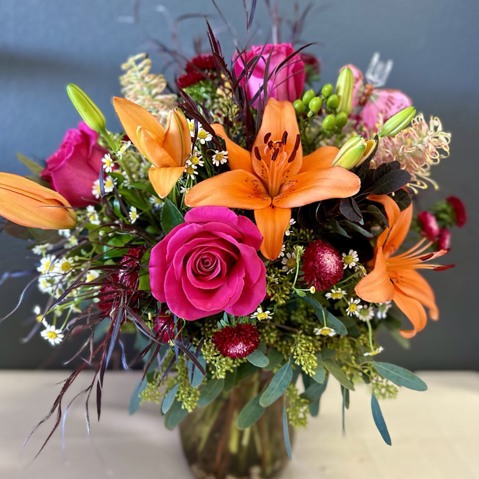 Bright bouquet of orange lilies and pink roses in a glass vase