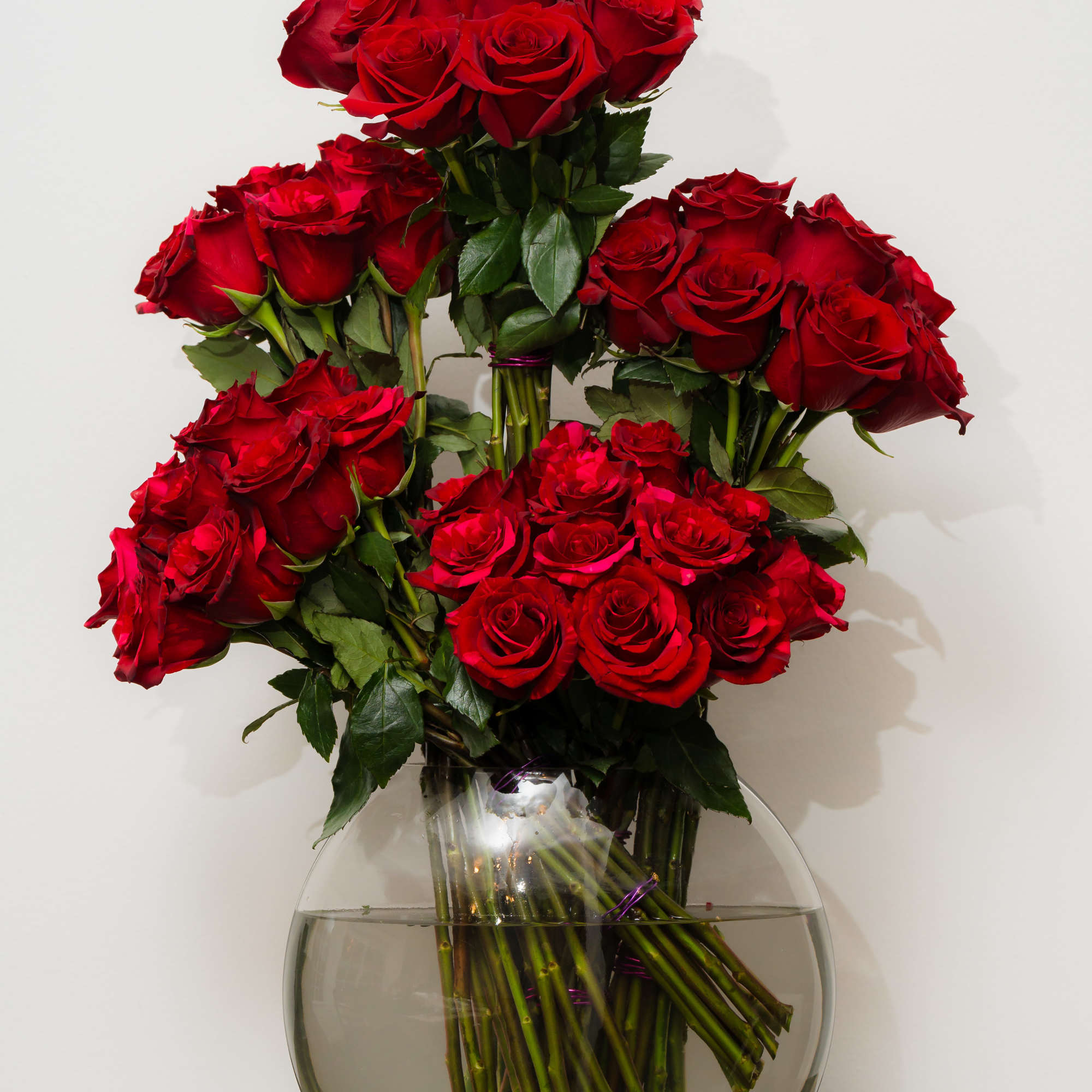 Red roses arranged in a clear glass vase
