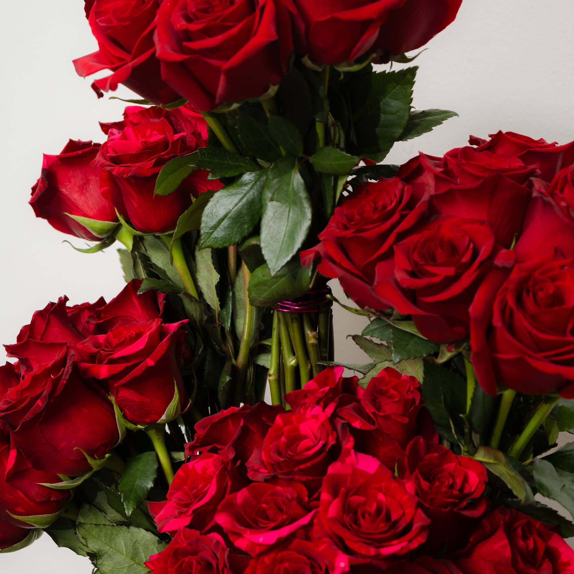 Bouquet of red roses with green foliage in a clear vase