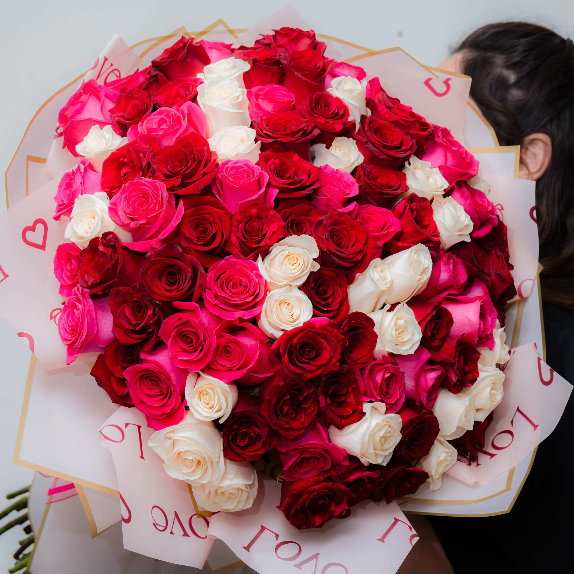 Large bouquet of red, pink, and white roses wrapped in printed paper, photo 5 of 10