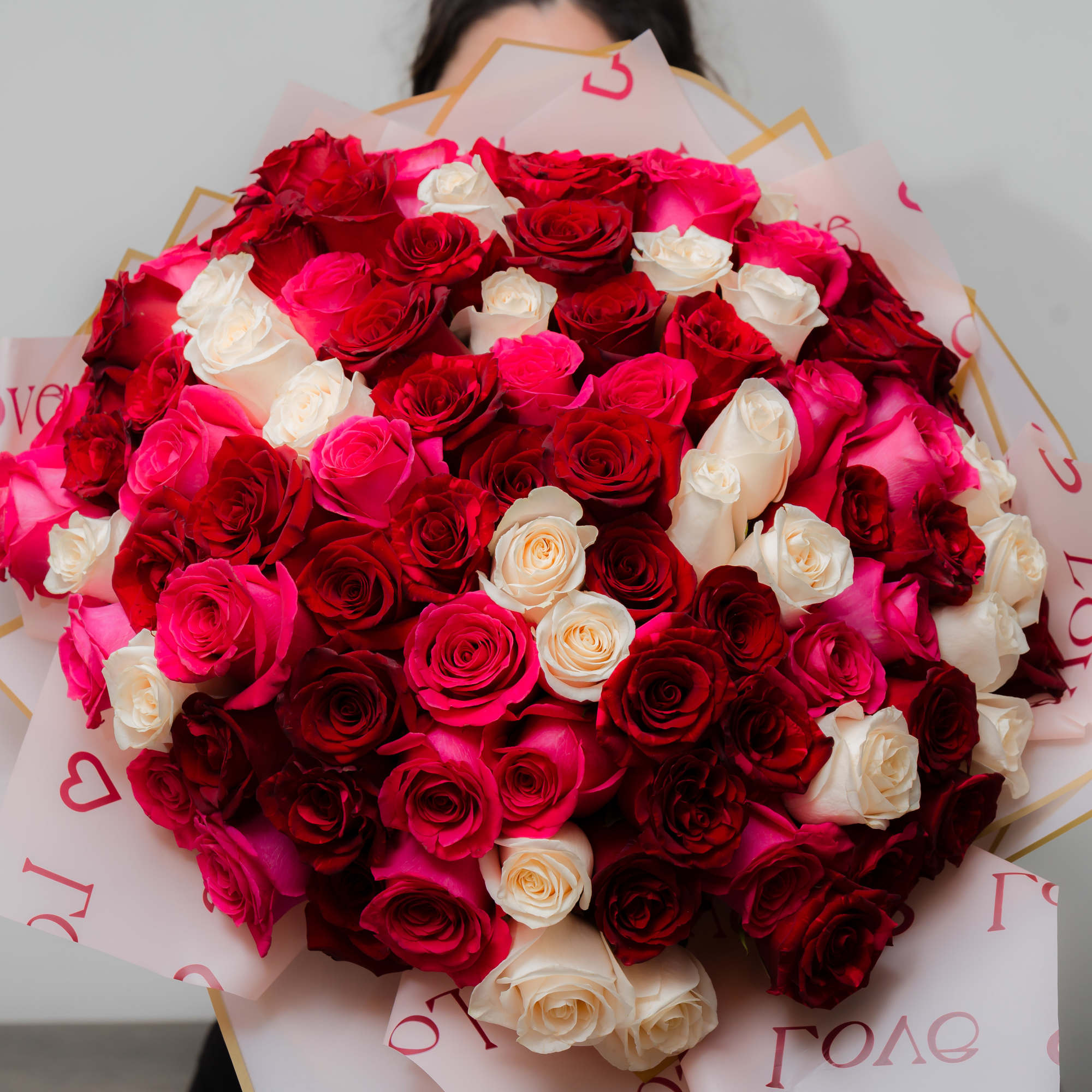 Large bouquet of red, pink, and white roses wrapped in printed paper