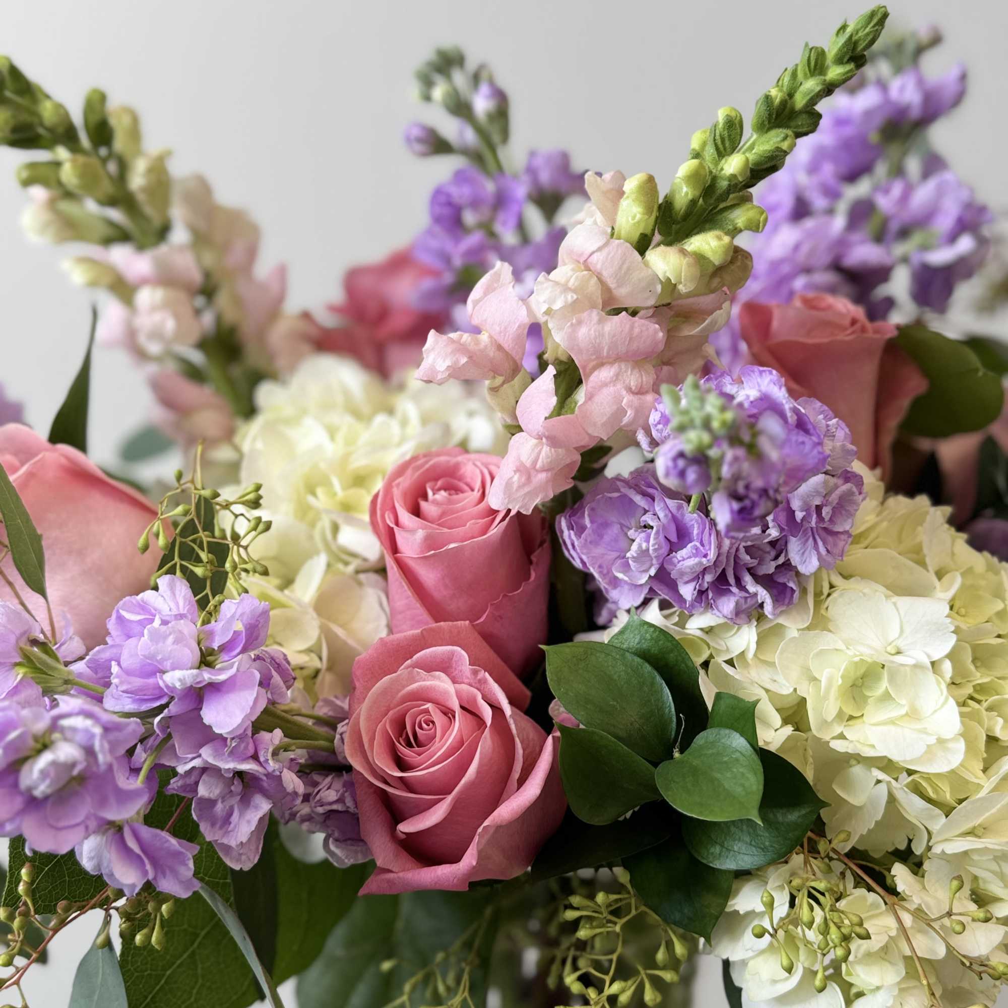 Pink roses and purple flowers arranged with white hydrangeas