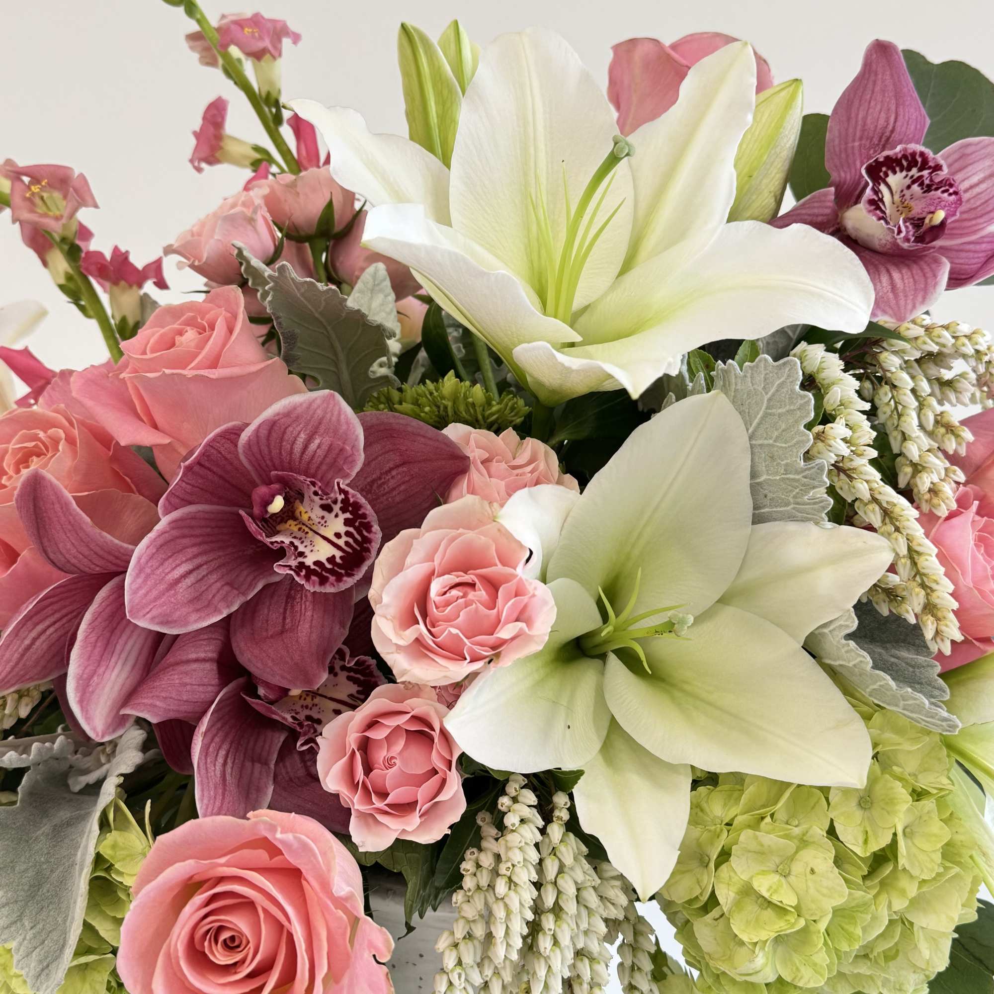 Pink roses and white lilies with purple orchids in a vase