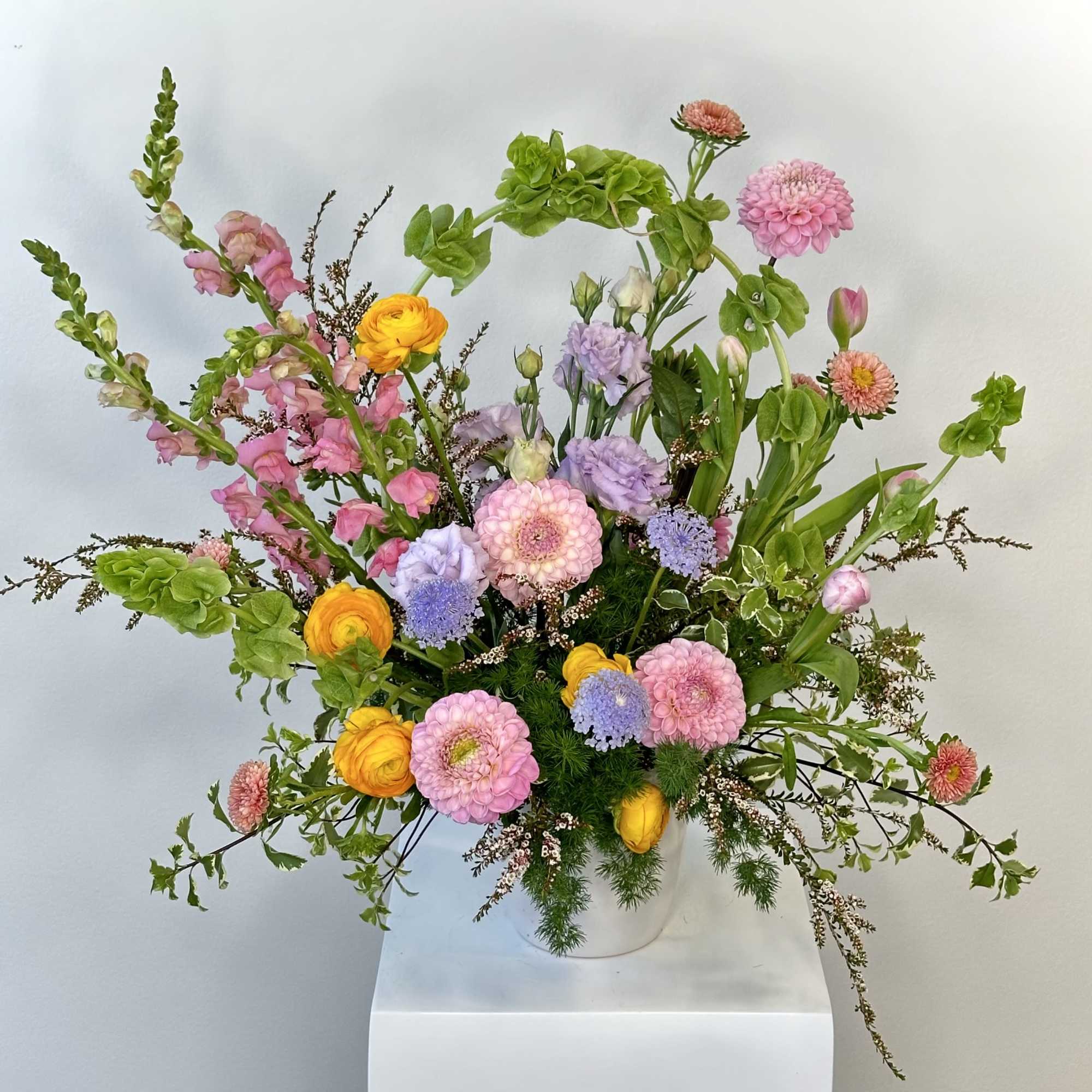 Colorful mixed bouquet in a white vase with pink, yellow, purple, and green blooms