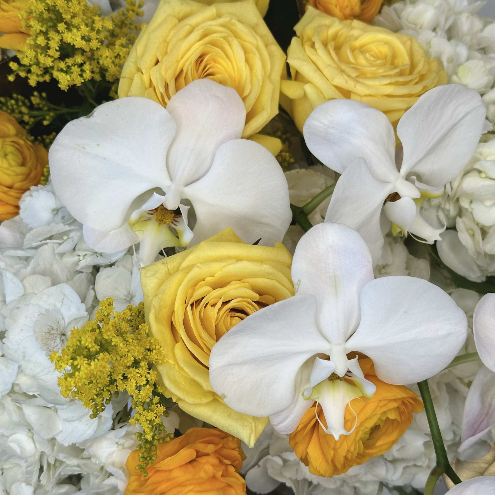 Yellow roses and white orchids in a mixed bouquet
