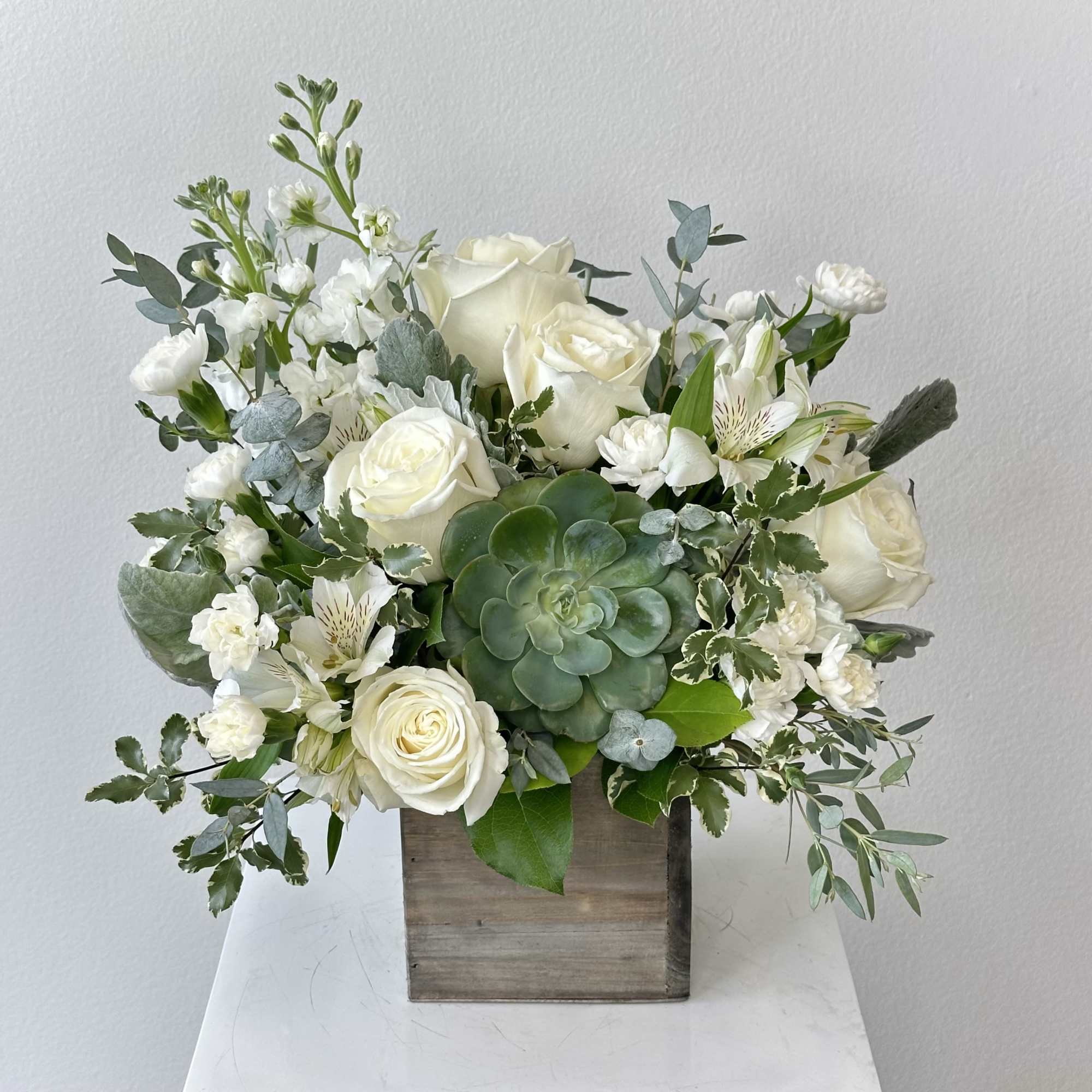 White rose arrangement with a succulent in a wooden box