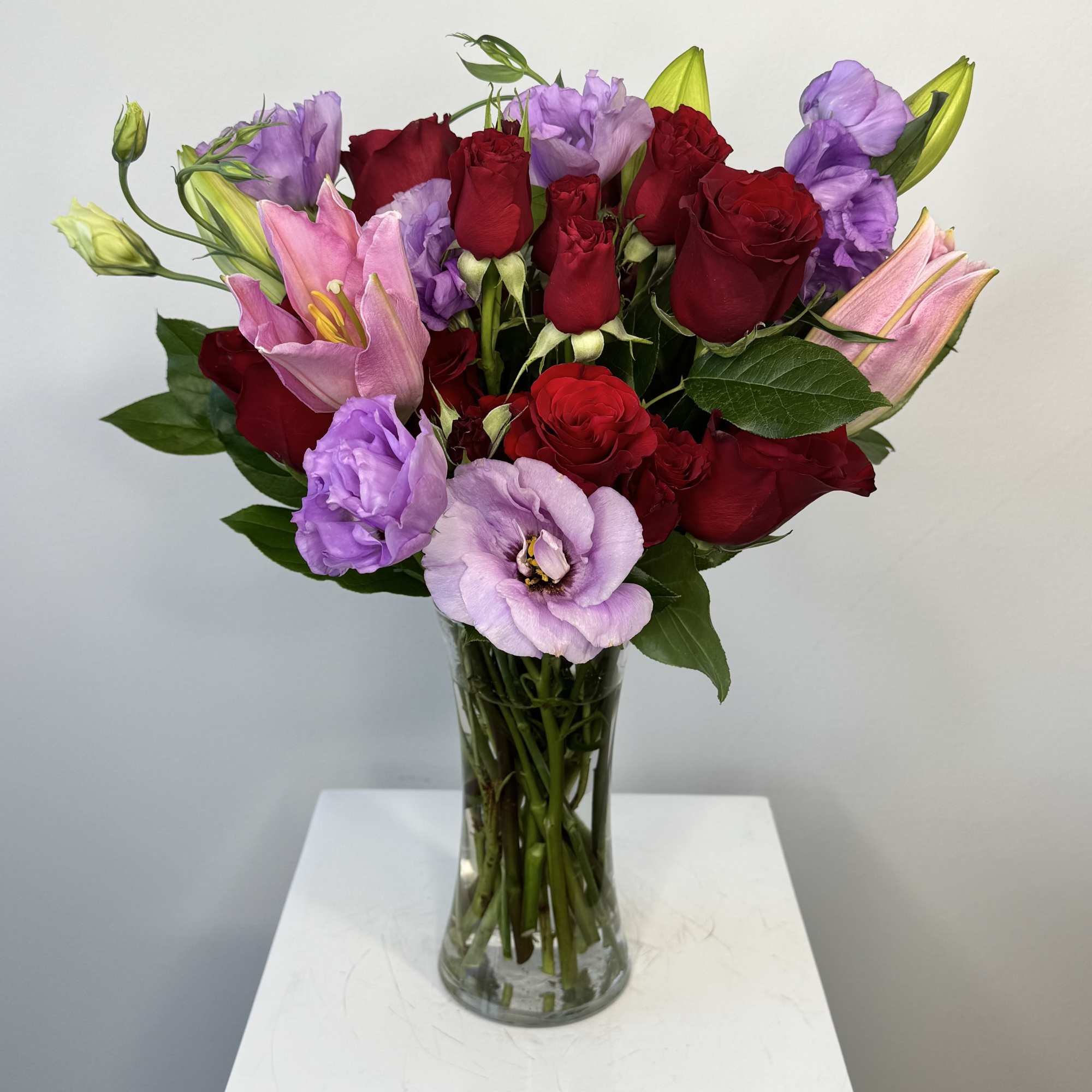 Bouquet of red roses and pink lilies in a clear glass vase