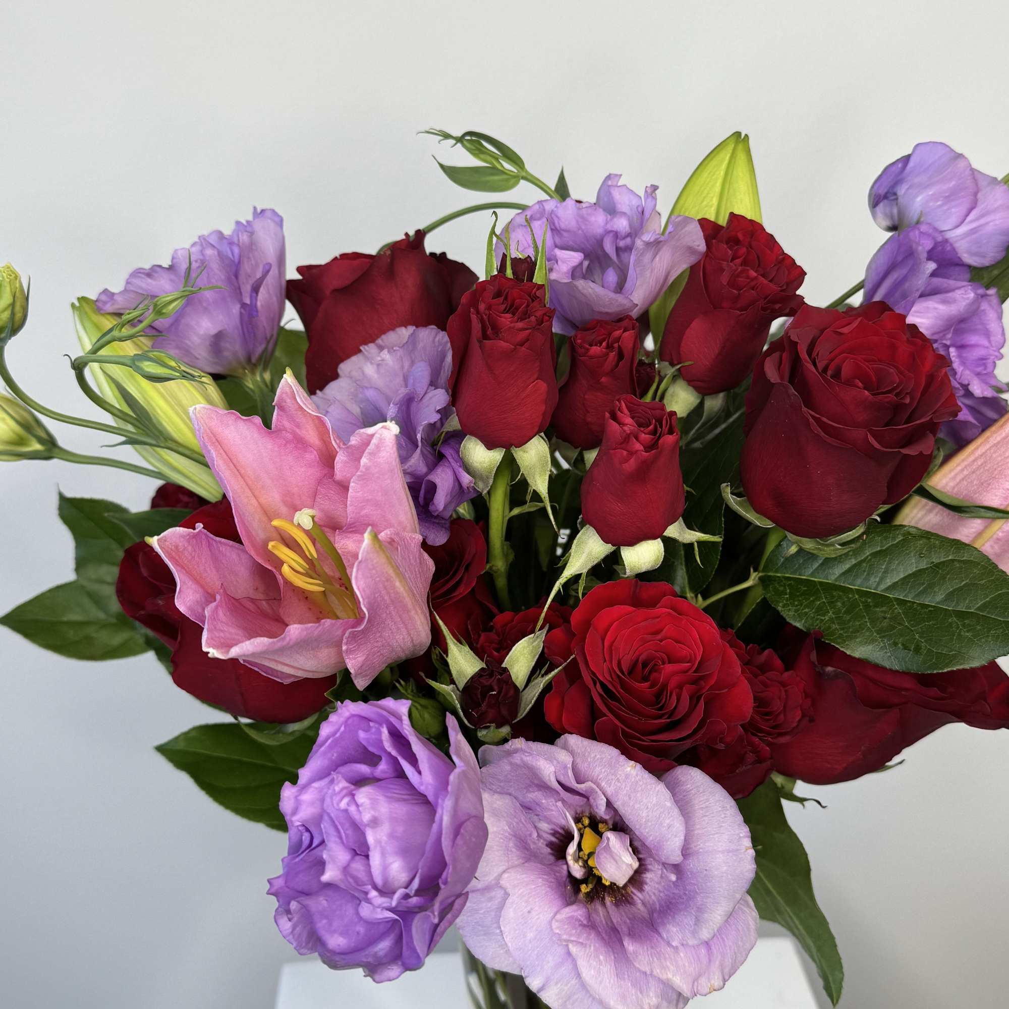 Bouquet of red roses and lavender flowers in a glass vase