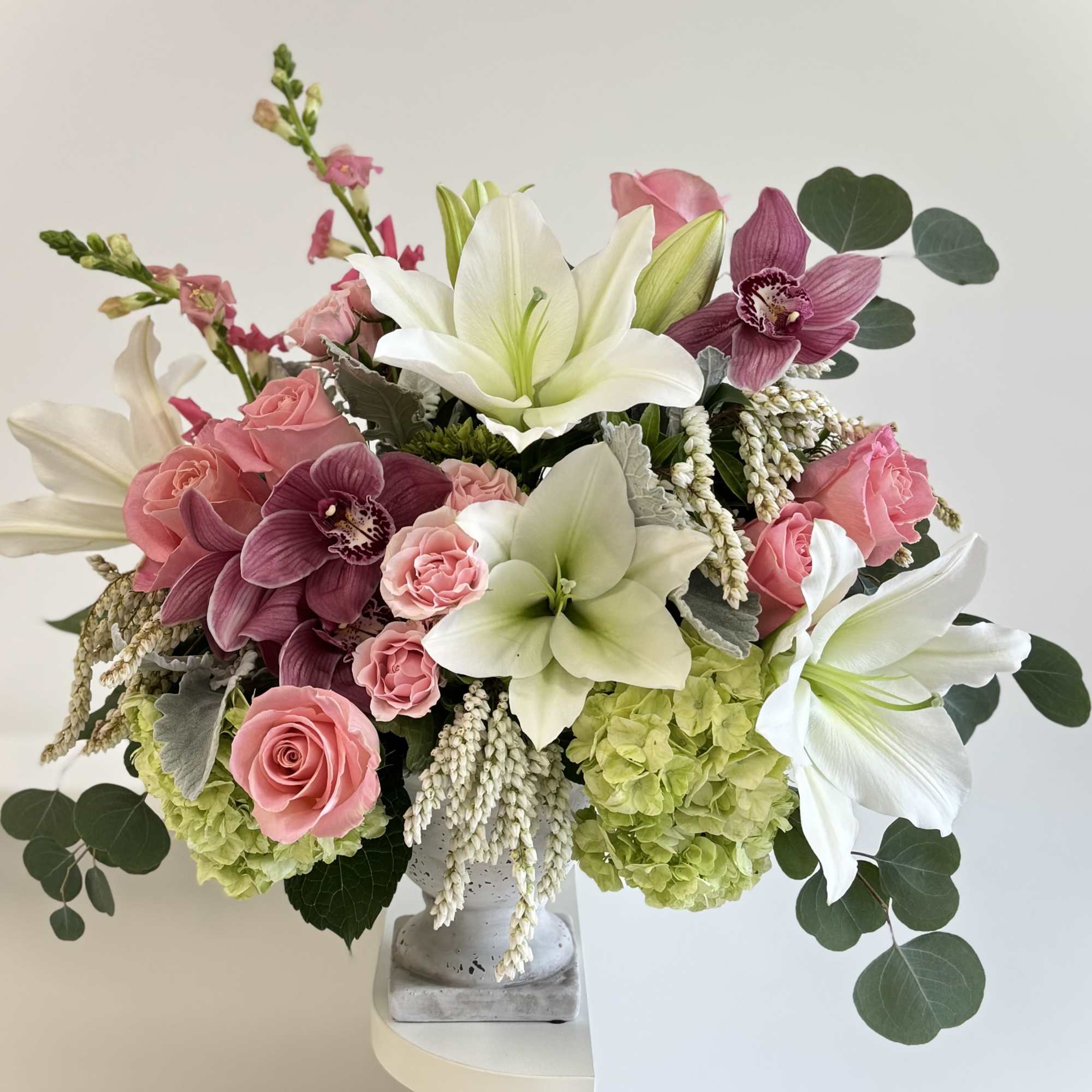 Pink roses and white lilies arranged in a gray vase