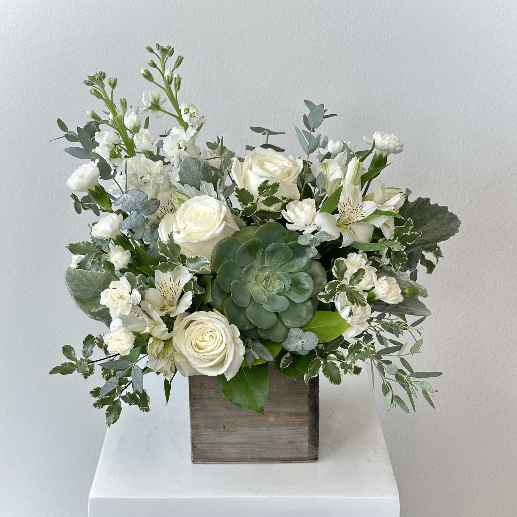 White roses and mixed white flowers in a wooden box with a succulent centerpiece