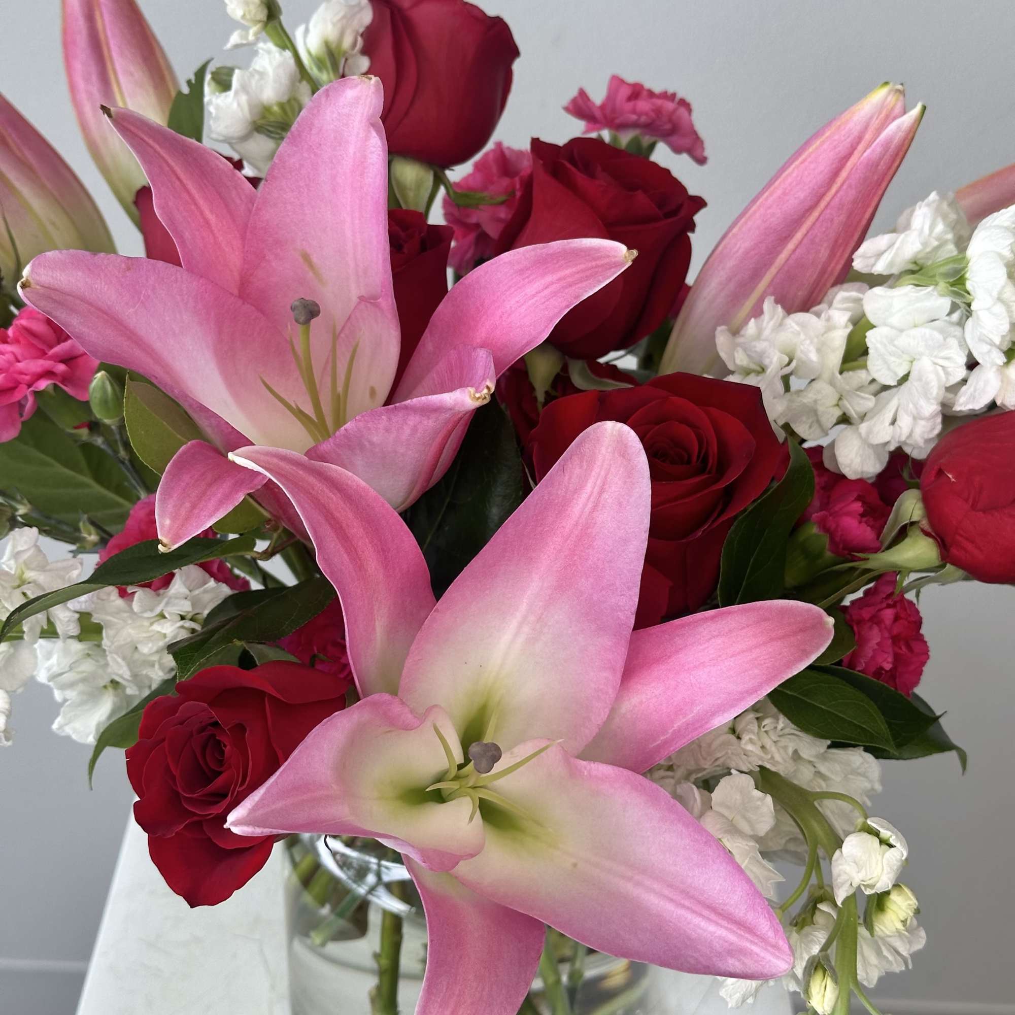 Pink lilies and red roses in a clear glass vase, photo 2 of 2