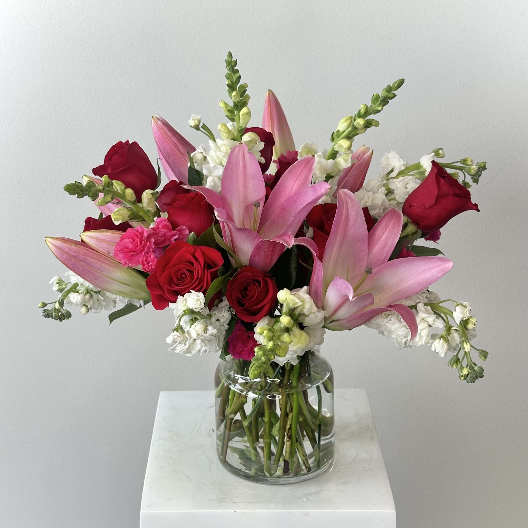 Bouquet of pink lilies and red roses in a clear glass vase