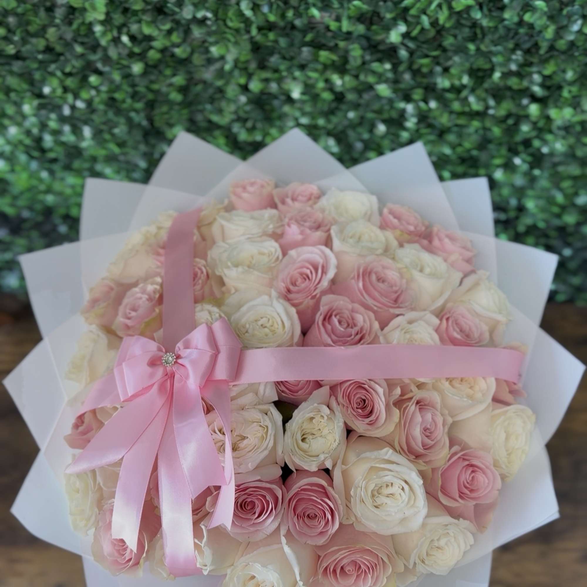 Bouquet of pink and white roses wrapped in white paper with a pink ribbon