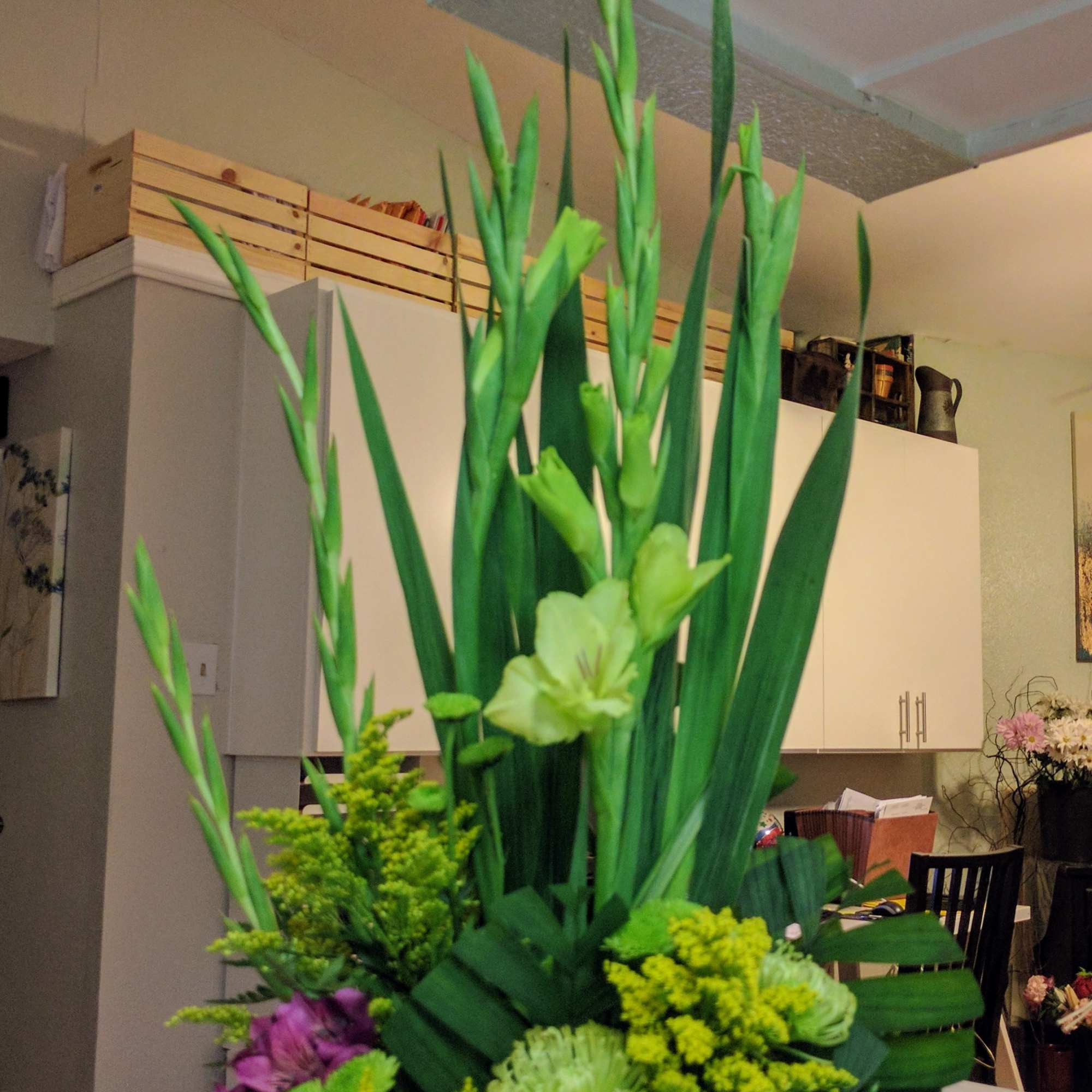 Tall floral arrangement with purple and green flowers in a black container