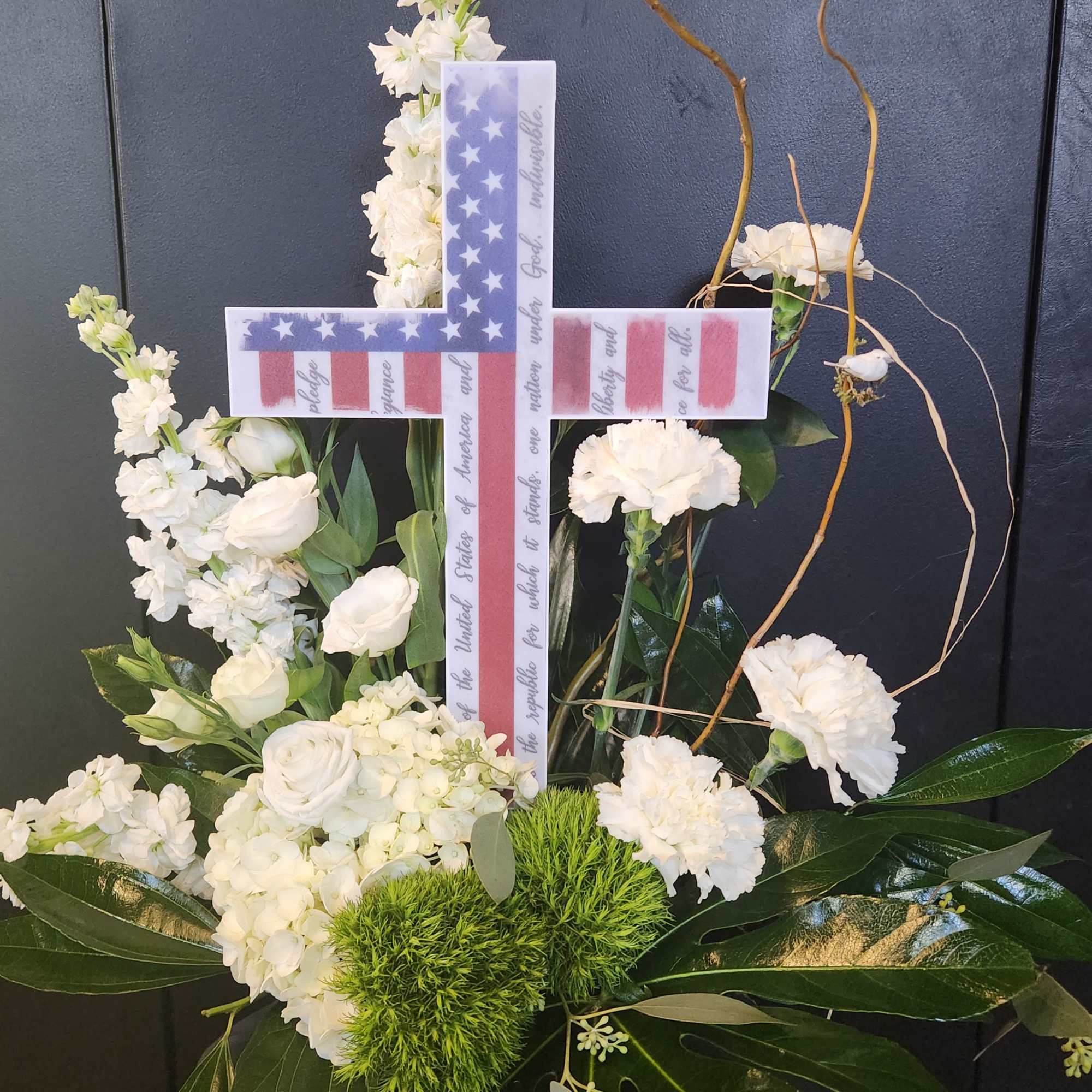 White floral cross arrangement with a patriotic ribbon design