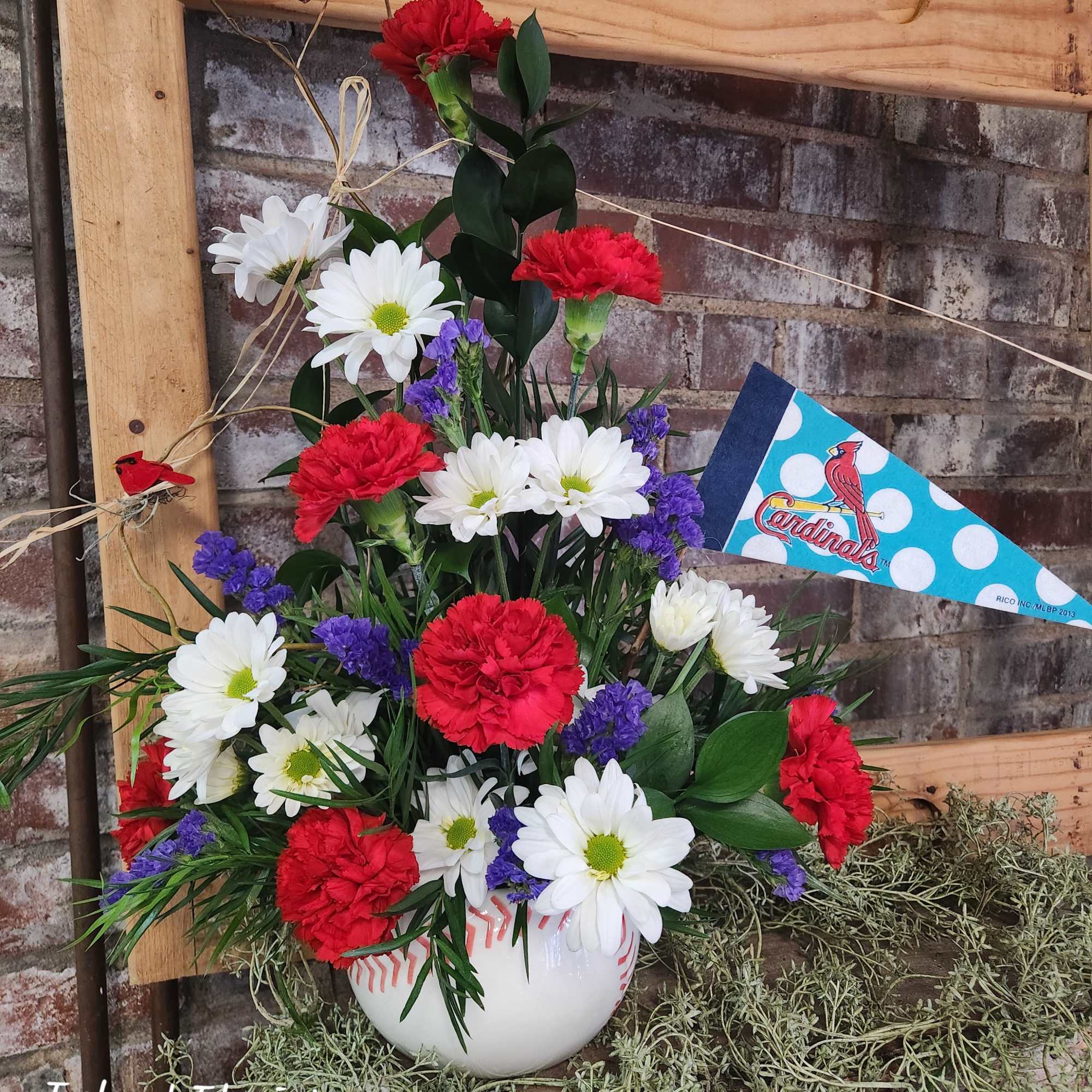 Red carnations and white daisies in a baseball vase