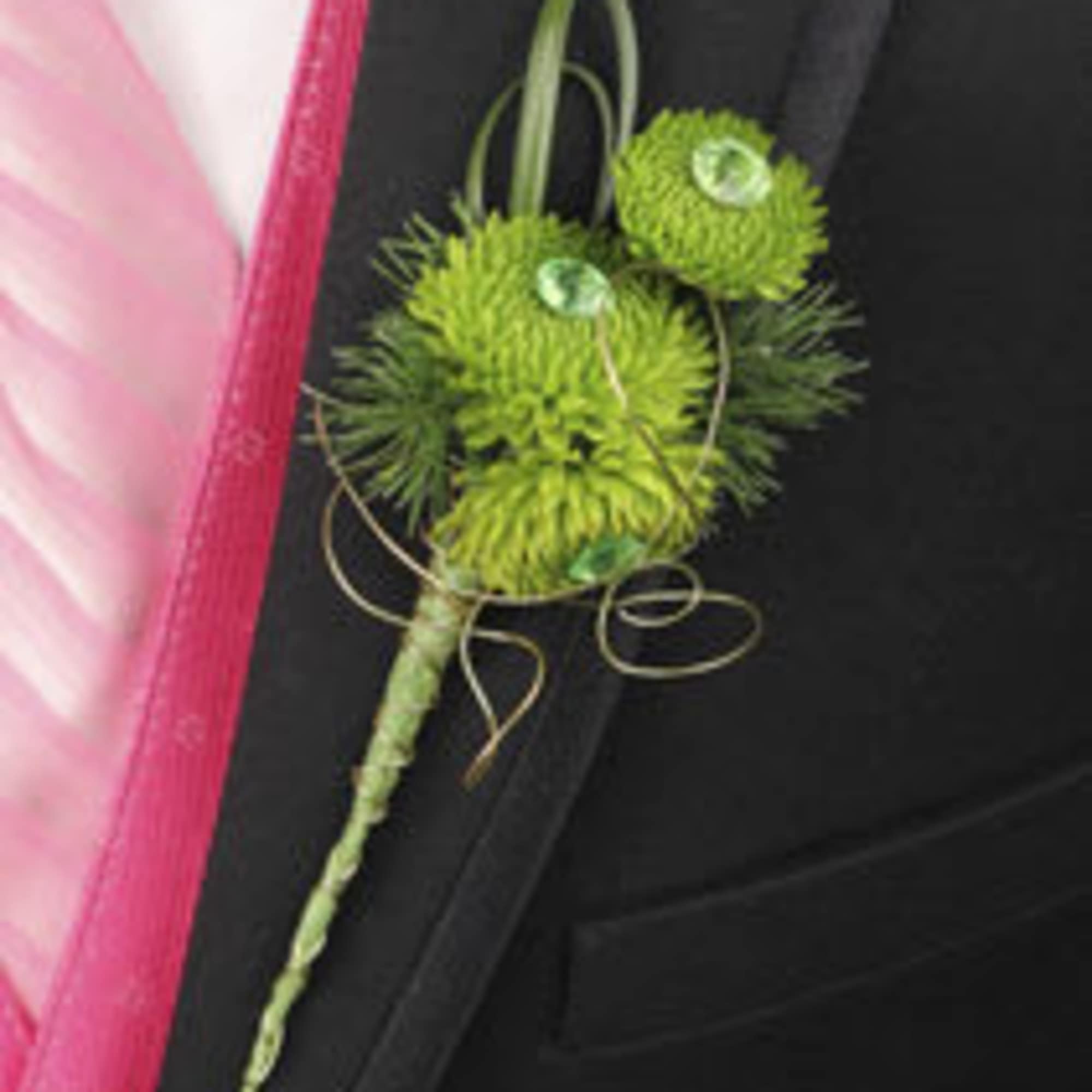 Green boutonniere with round blooms and ribbon on a black suit