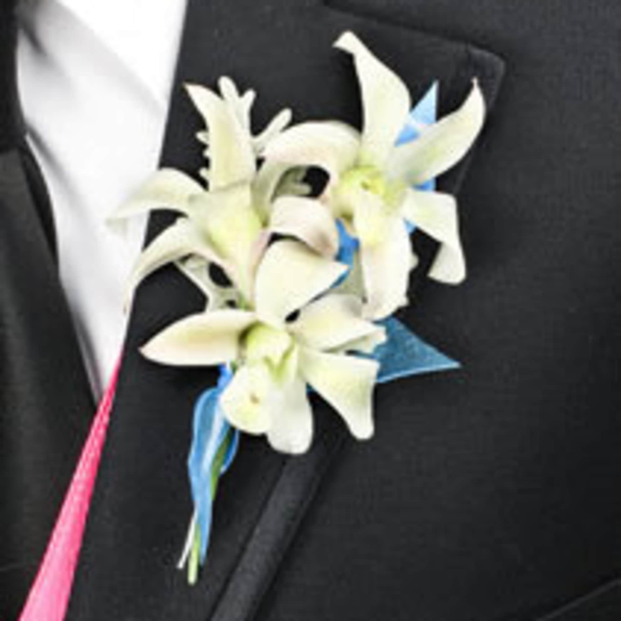 White orchid boutonniere with blue ribbon on a black suit lapel