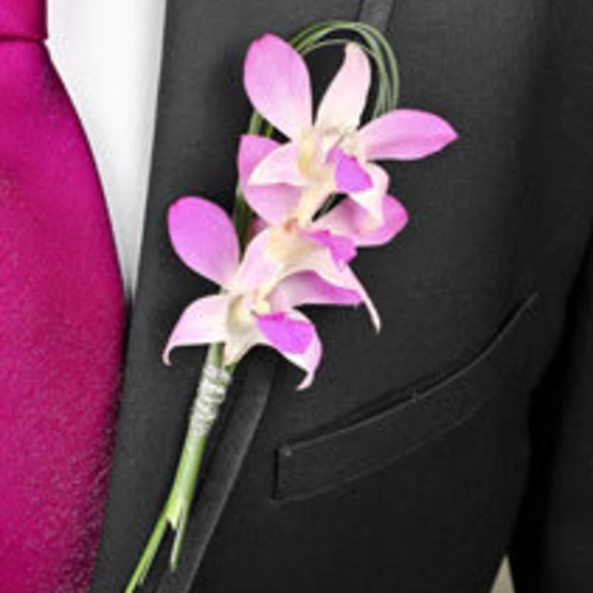 Pink orchid boutonniere pinned to a black suit jacket, photo 13 of 19