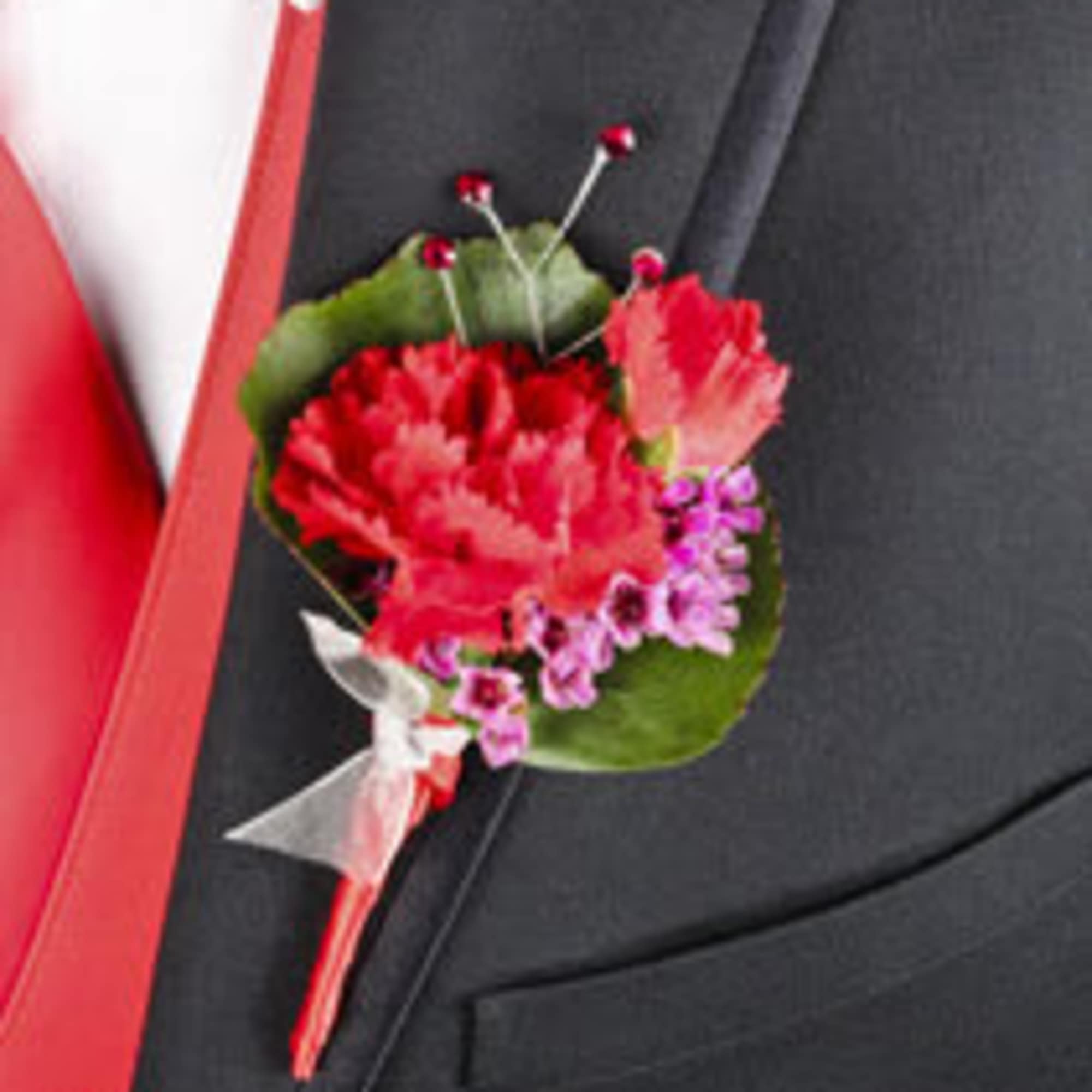Red boutonniere with small purple flowers pinned to a dark suit