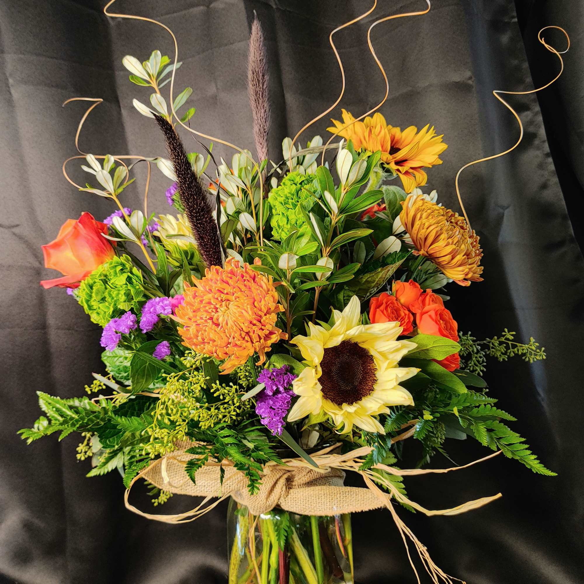 Mixed bouquet in a glass vase with sunflowers, roses, and chrysanthemums