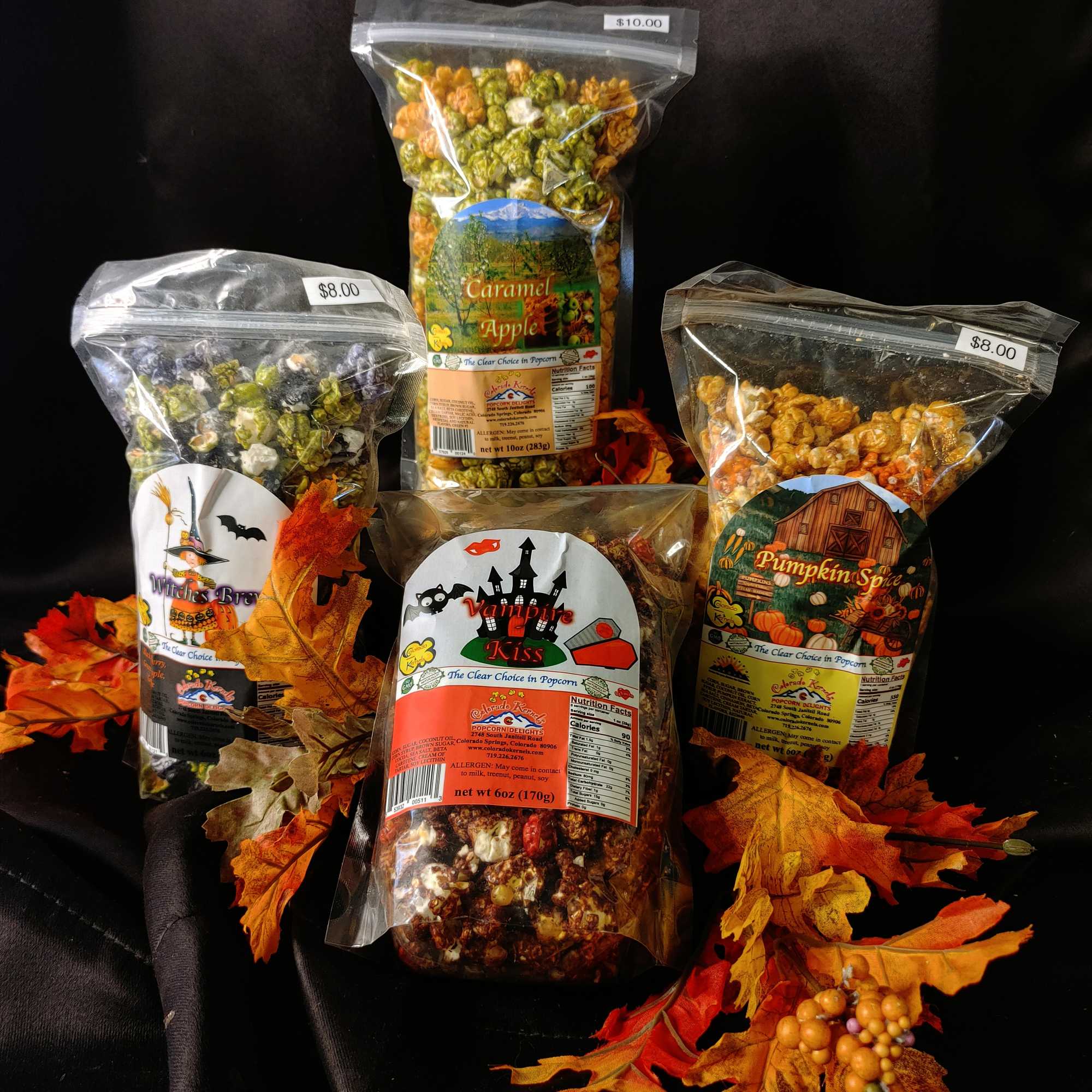 Four bags of flavored popcorn arranged with autumn leaves on a black background.