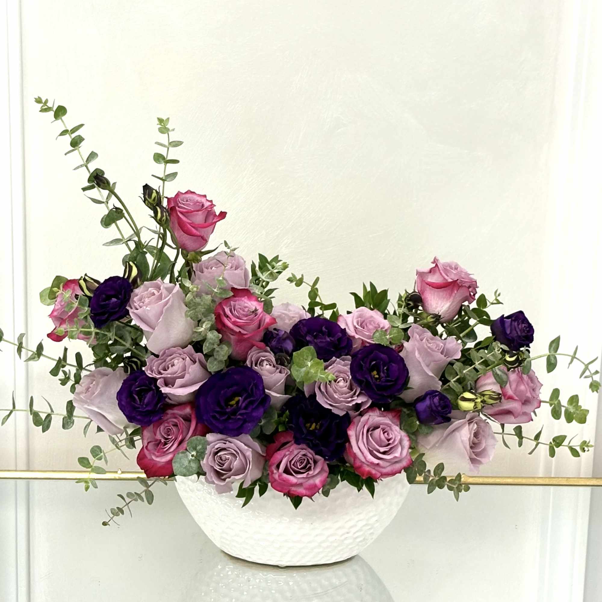 Pink and lavender roses arranged in a white bowl vase