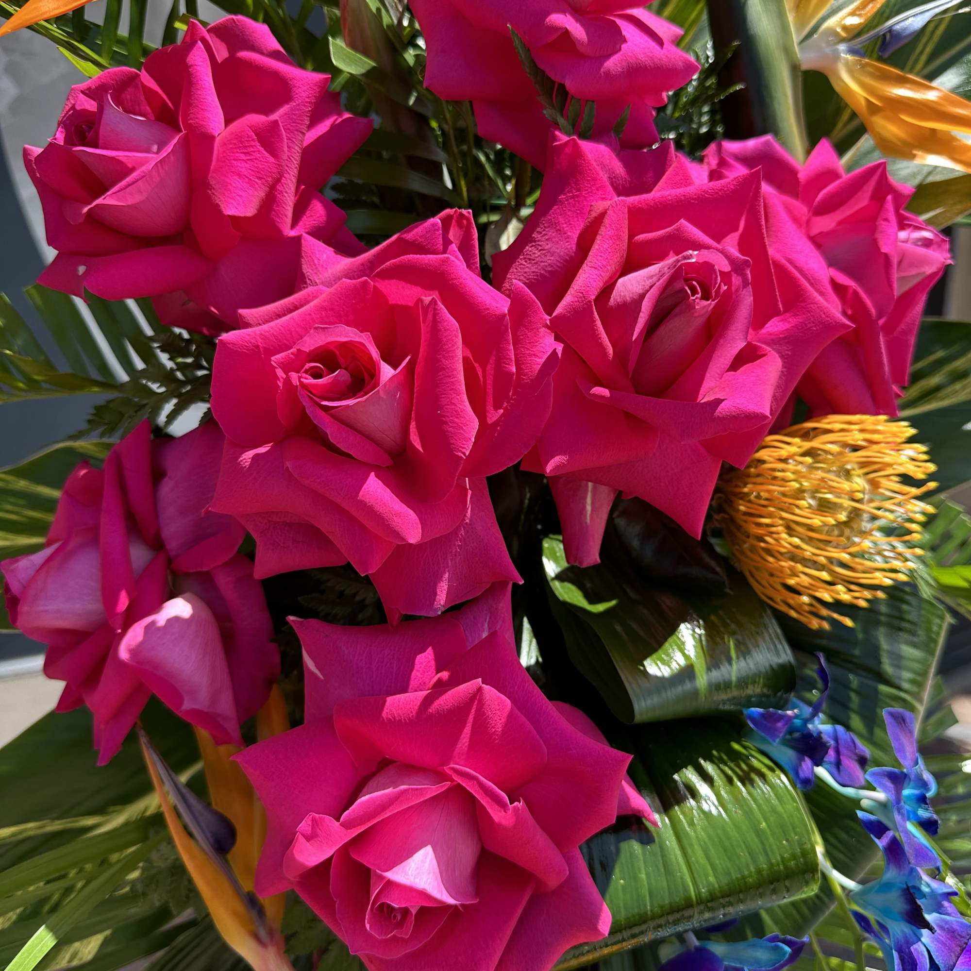 Bright pink roses with tropical flowers and foliage