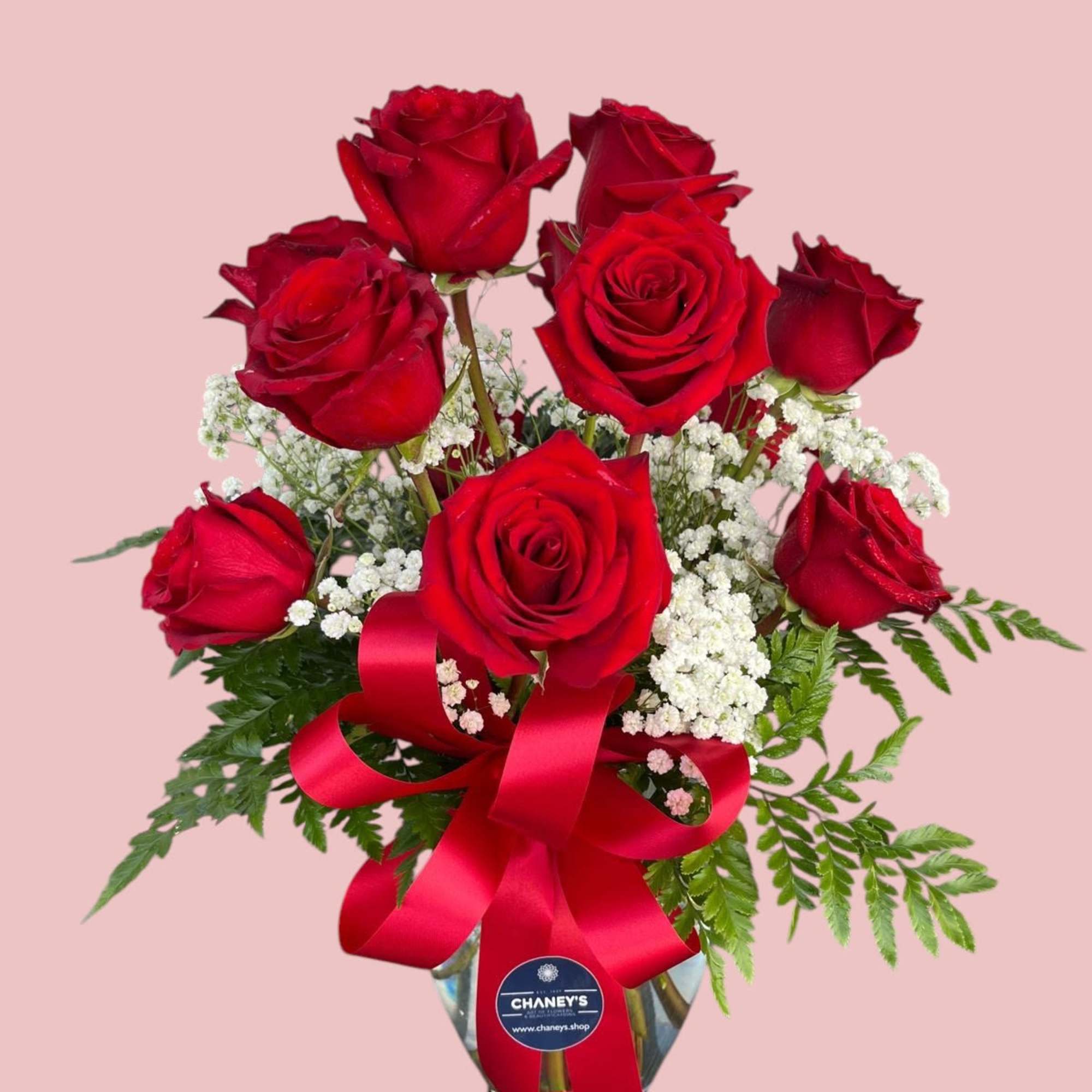 Bouquet of red roses with baby's breath in a glass vase and red ribbon
