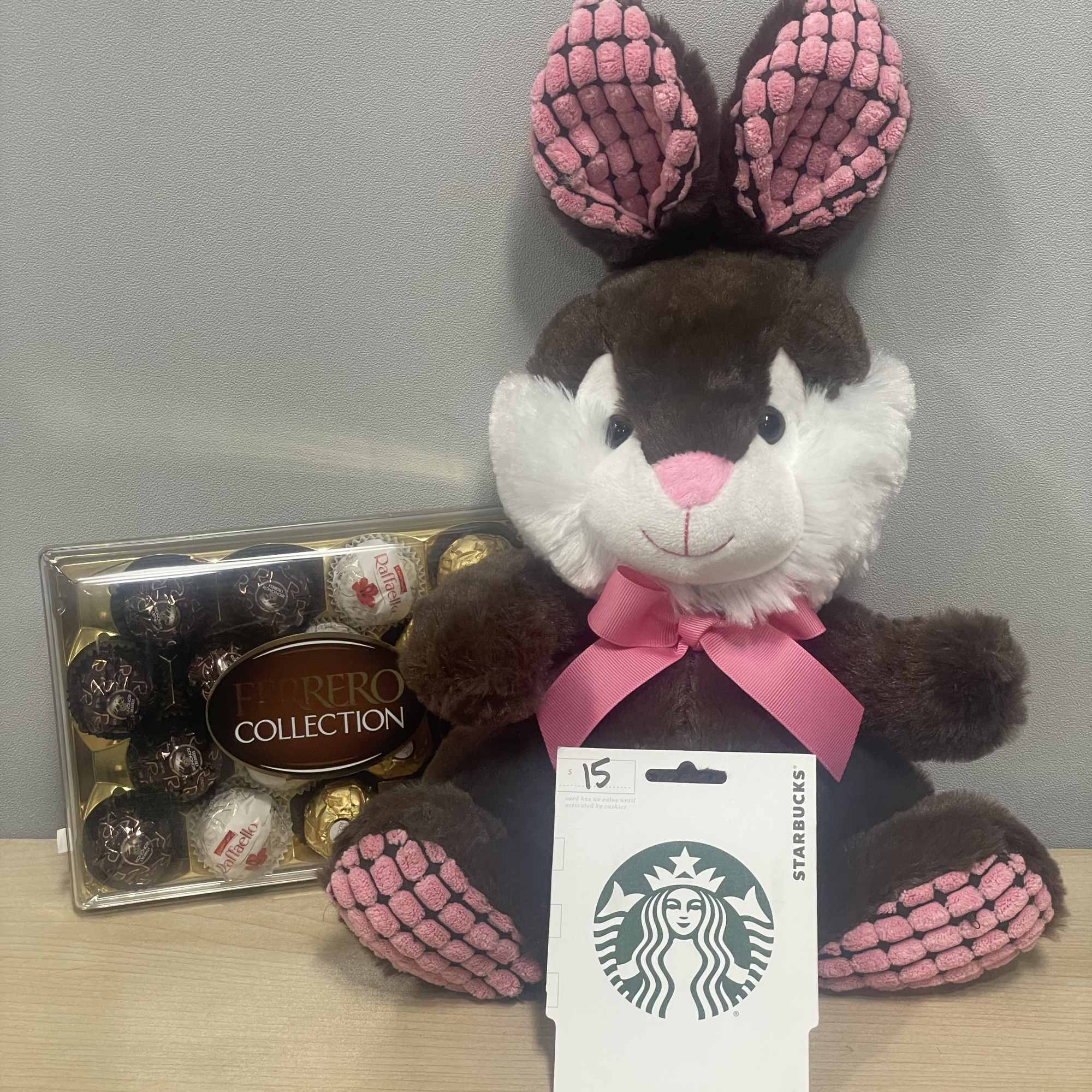 Plush bunny with a pink ribbon beside a Ferrero Rocher box and Starbucks card