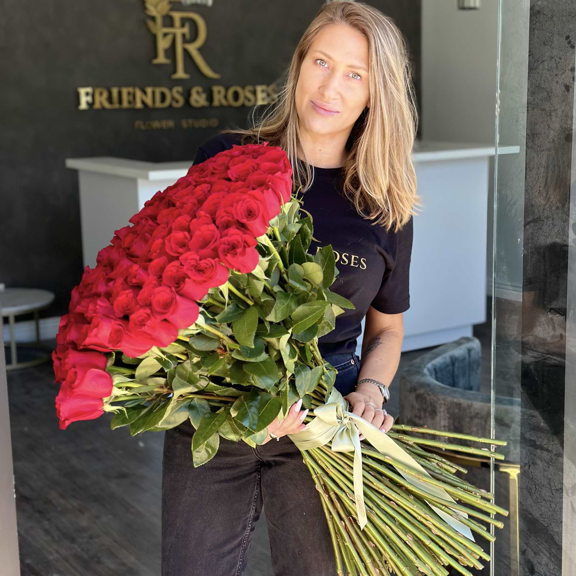 Woman holding a large bouquet of red roses tied with a ribbon