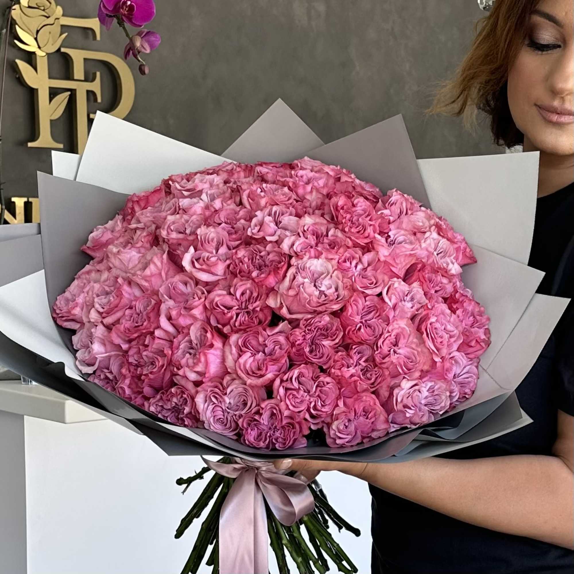 Large bouquet of pink roses wrapped in gray paper with a satin ribbon