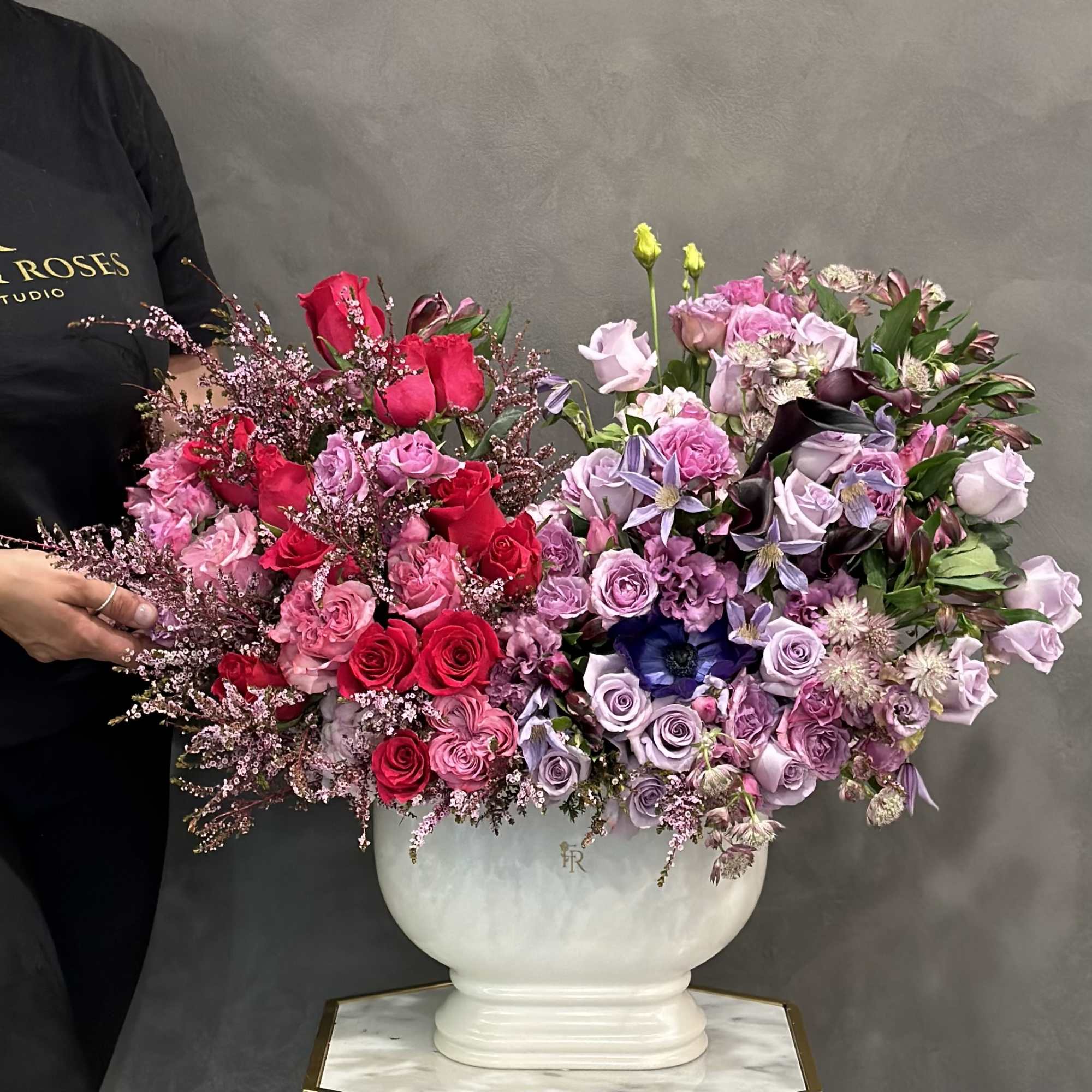 Large pink and purple floral arrangement in a white vase