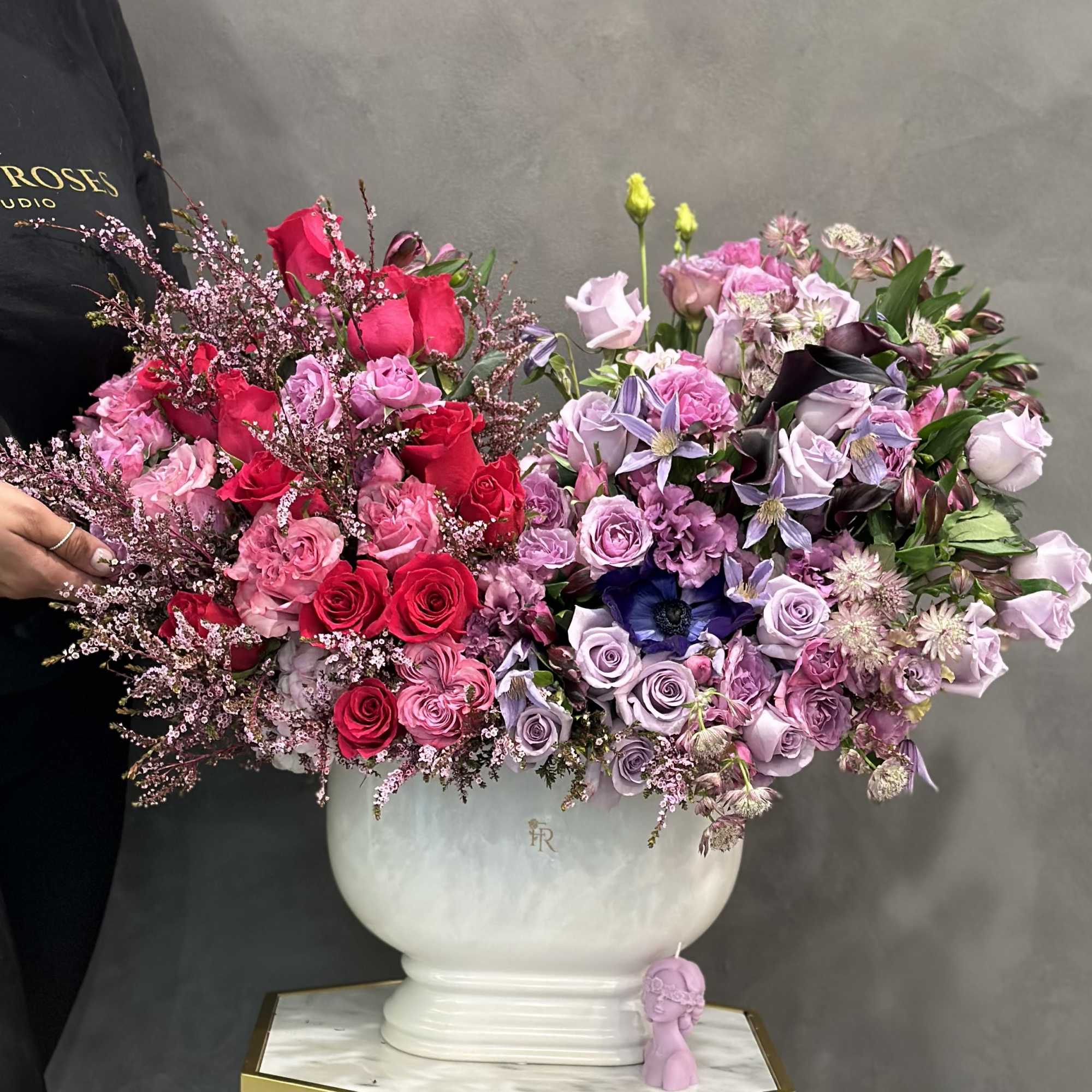 Large mixed bouquet of pink, red, and lavender flowers in a white vase
