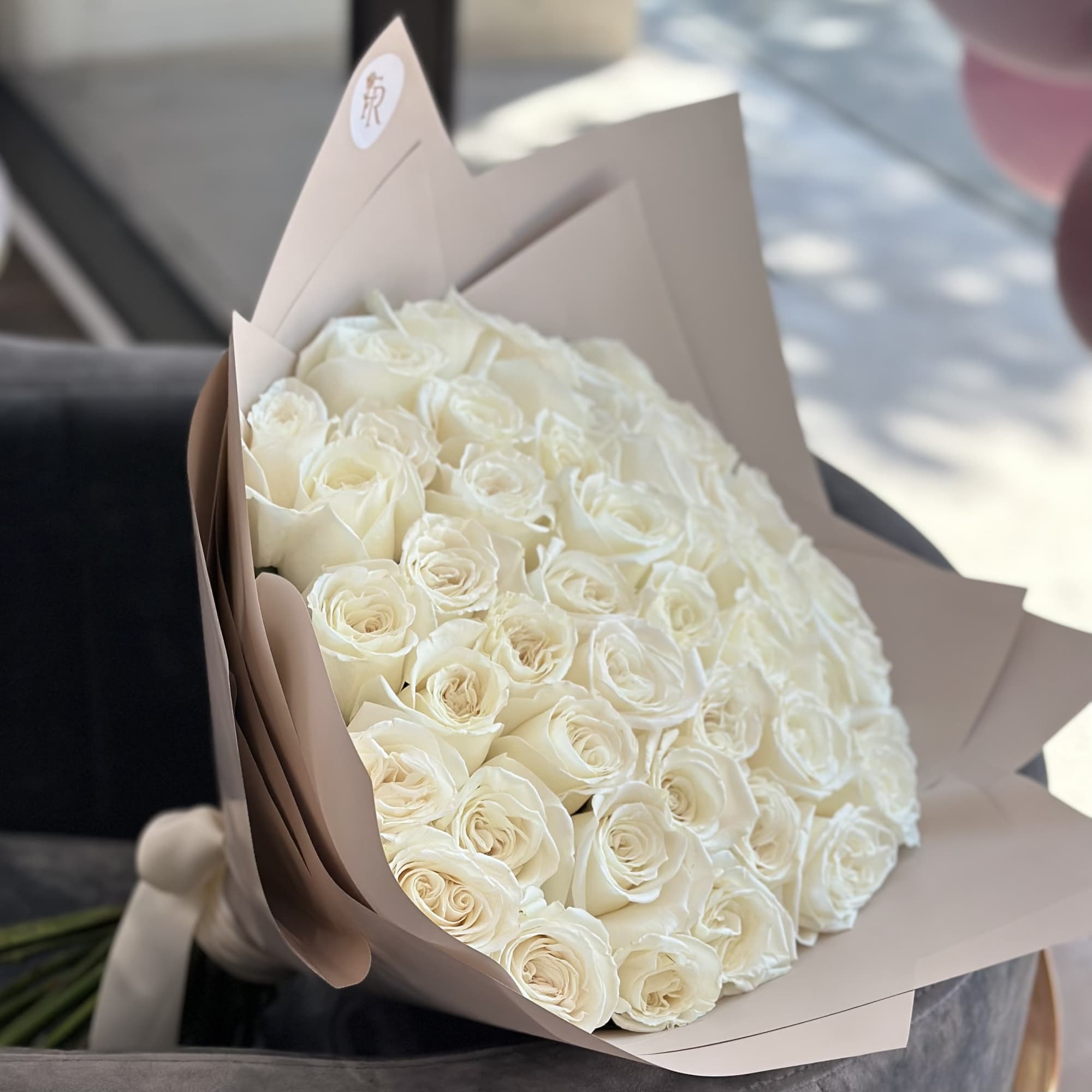Large bouquet of white roses wrapped in beige paper, photo 2 of 3