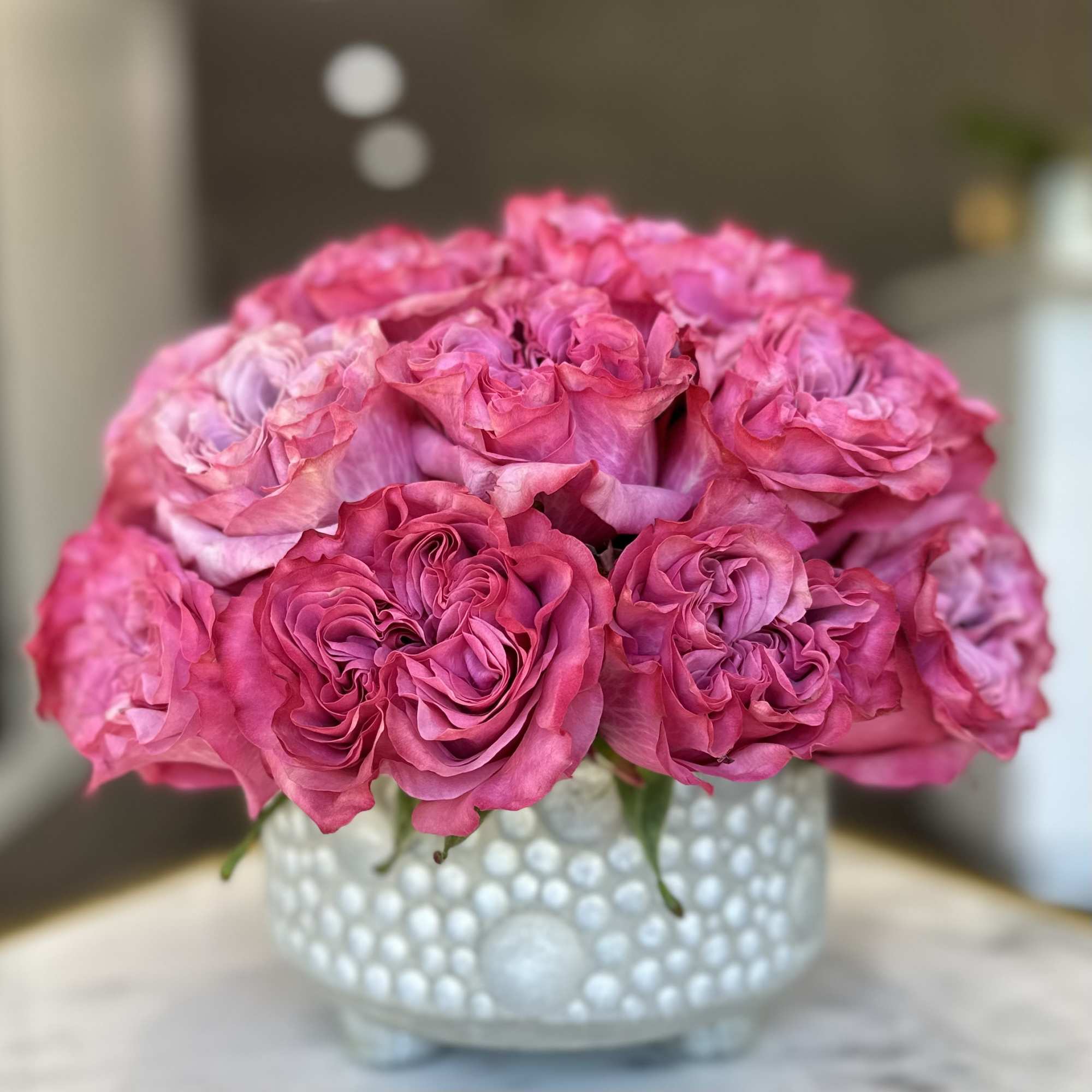 Pink roses arranged in a white textured vase
