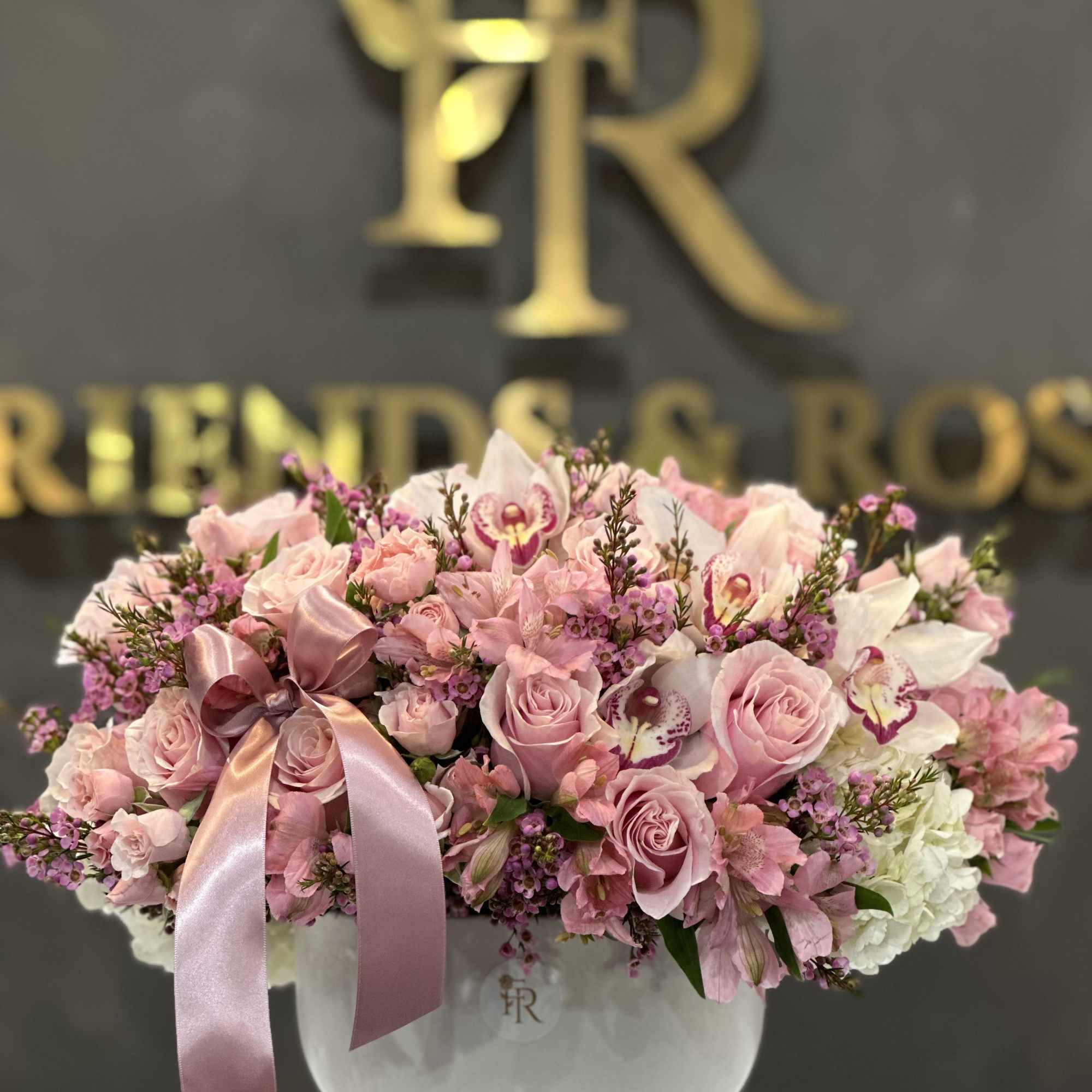Pink roses and orchids arranged in a white vase with a satin ribbon, photo 2 of 2