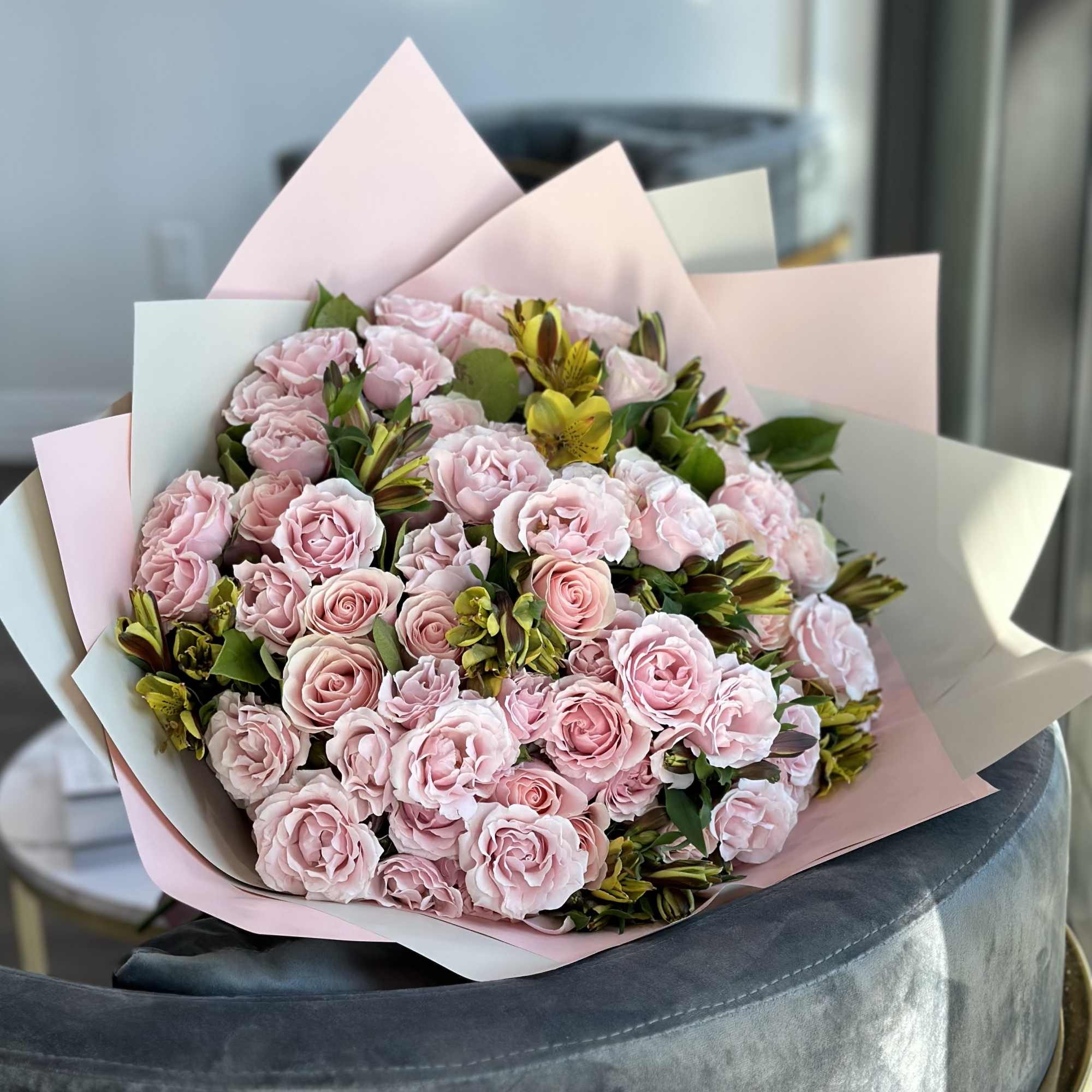 Bouquet of pale pink roses and yellow alstroemeria wrapped in pastel paper