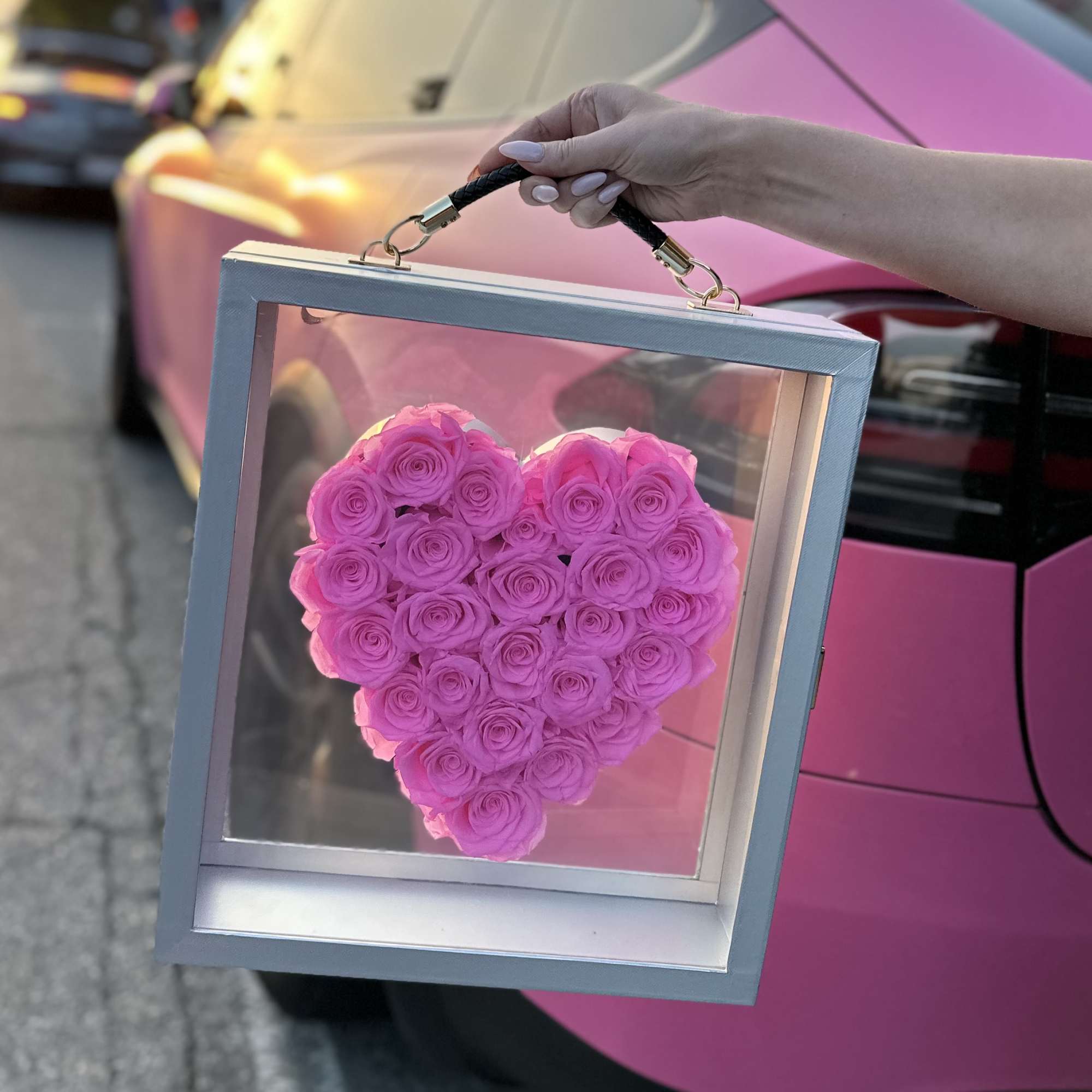 Heart-shaped pink rose arrangement in a clear display box