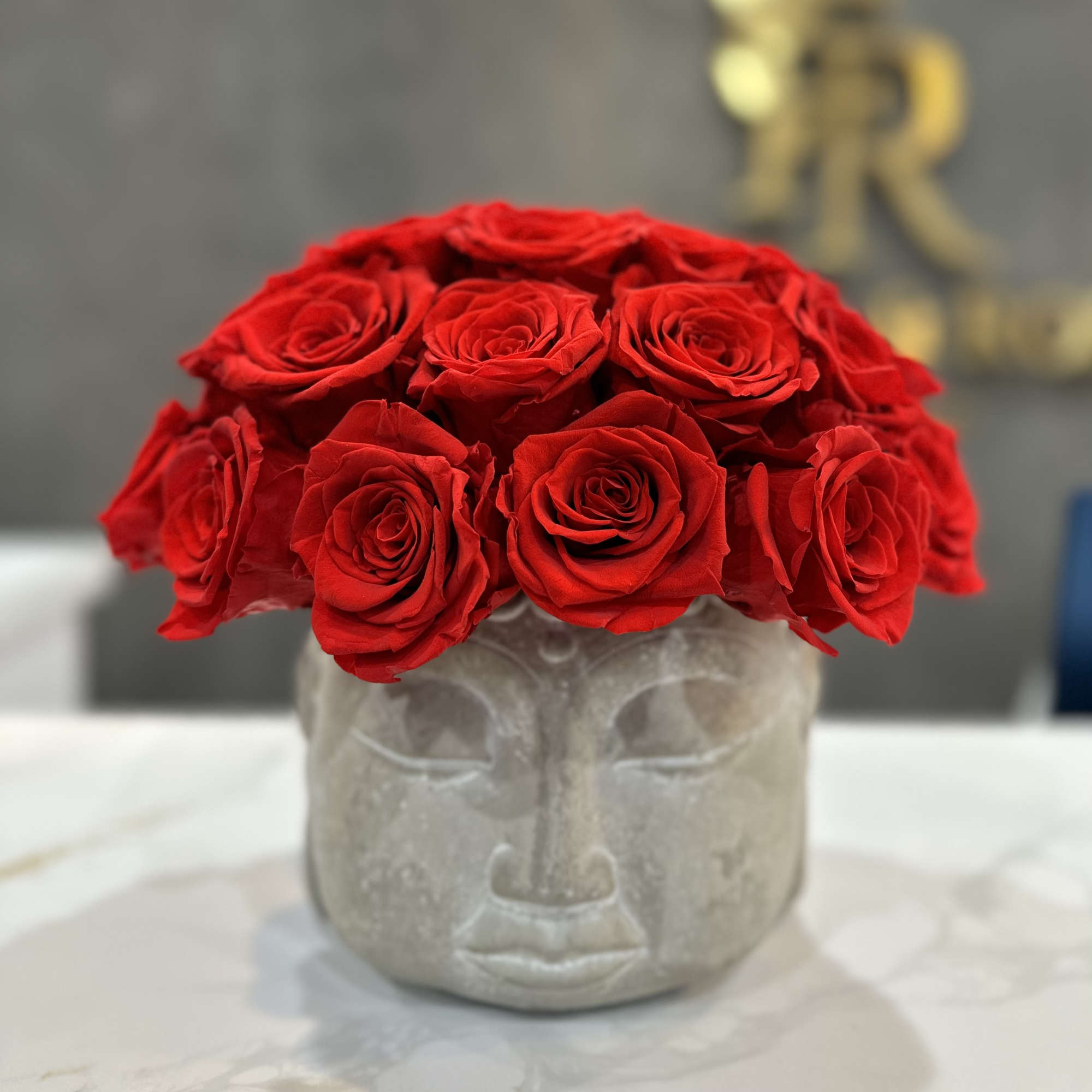 Red roses arranged in a gray face-shaped vase