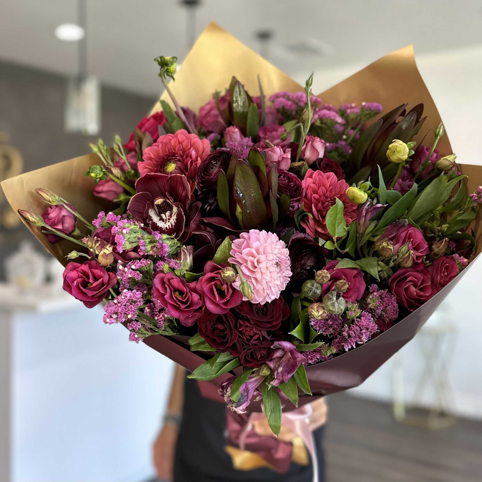 Bouquet of pink and burgundy flowers wrapped in brown paper