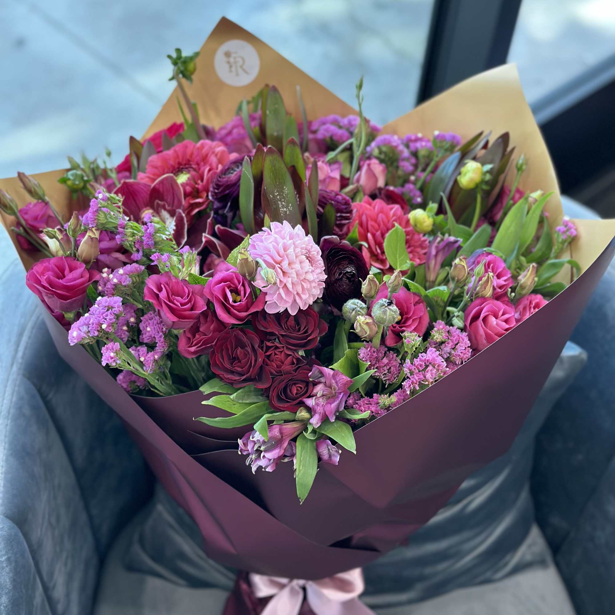 Bouquet of pink and purple flowers wrapped in burgundy paper