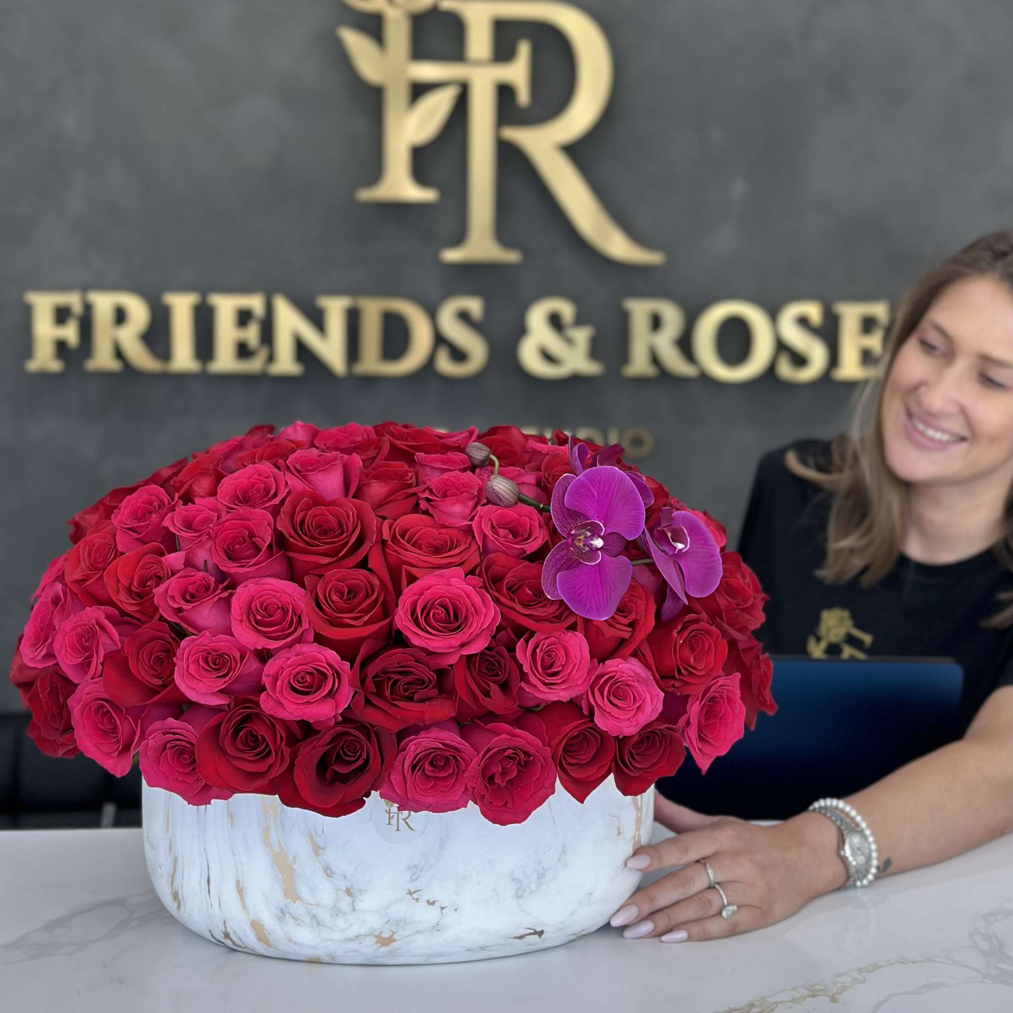Large bouquet of hot pink roses in a white vase with purple orchids