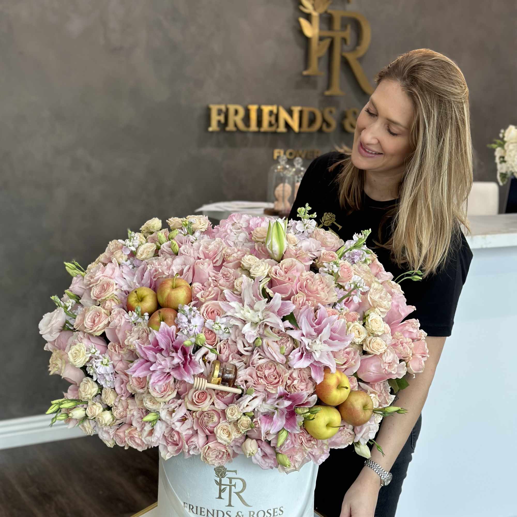 Large pink floral arrangement in a white hatbox with apples