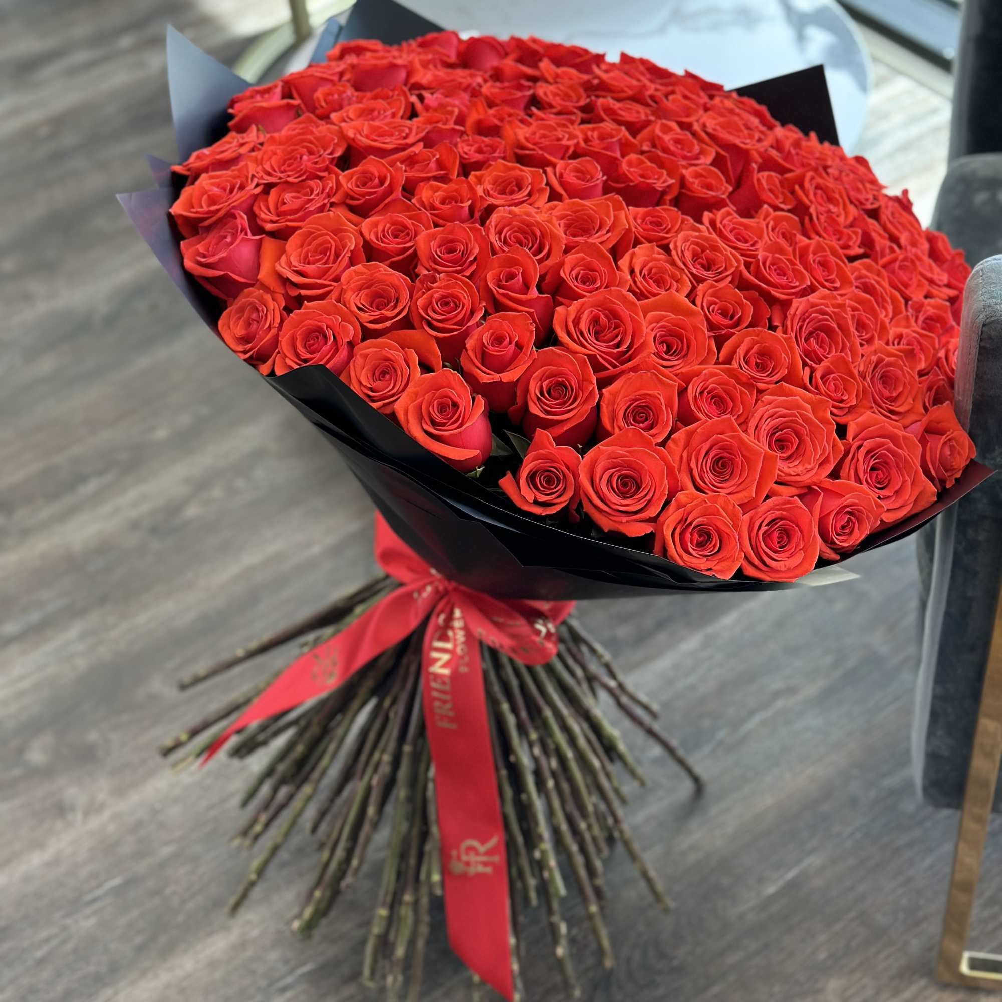 Large bouquet of red roses wrapped in black paper with a red ribbon, photo 3 of 3
