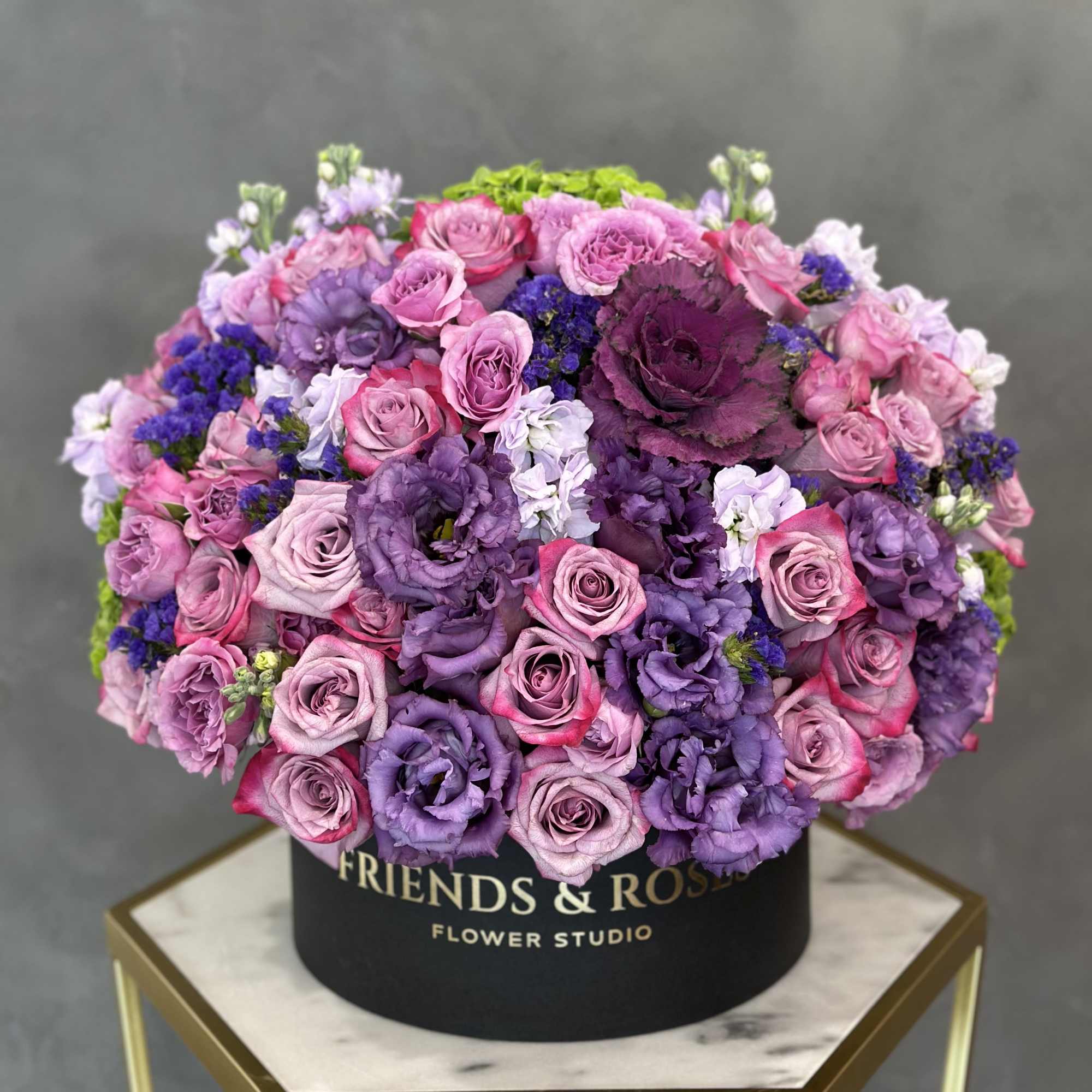 Round box arrangement of pink and purple roses and lisianthus