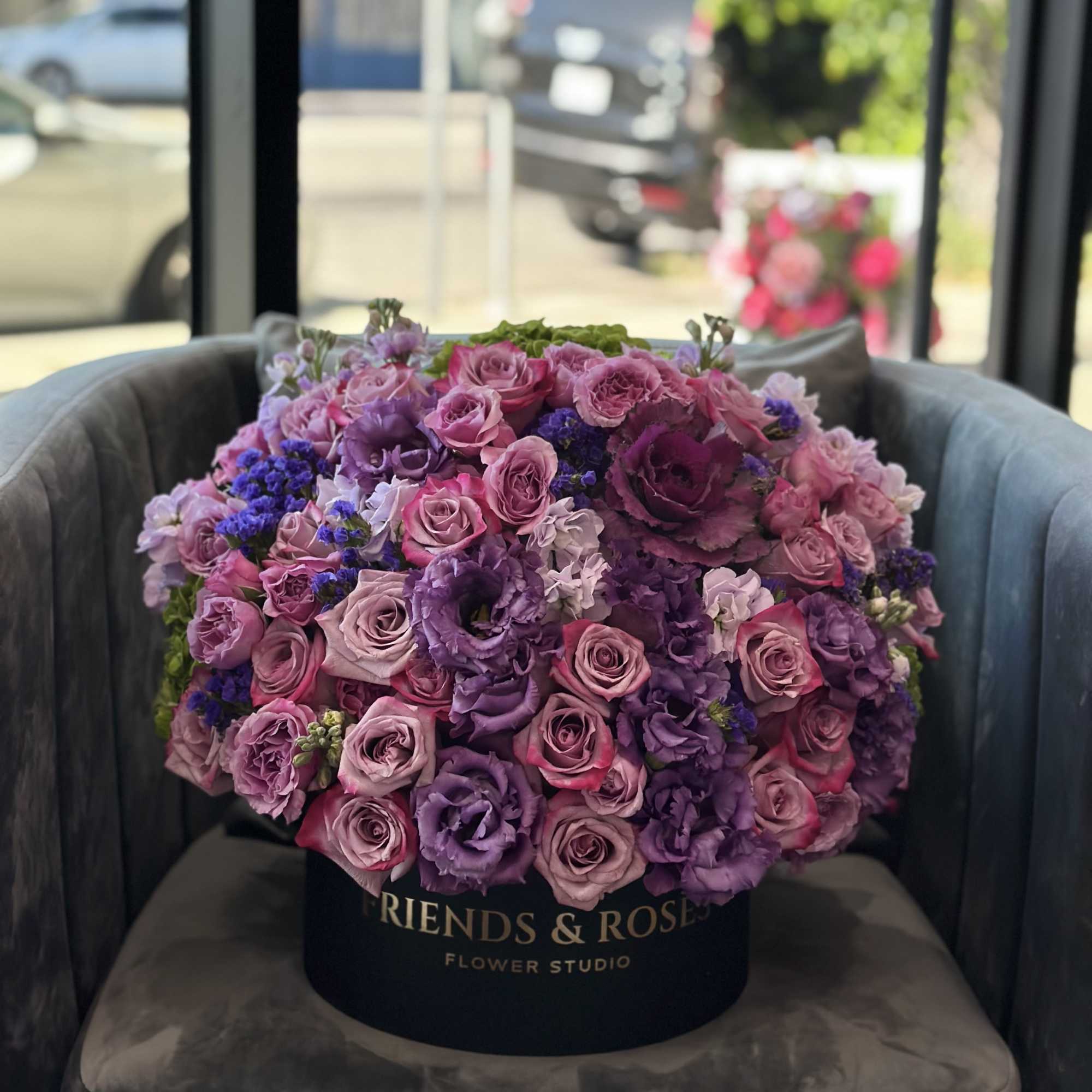 Large bouquet of pink and purple roses in a black hat box