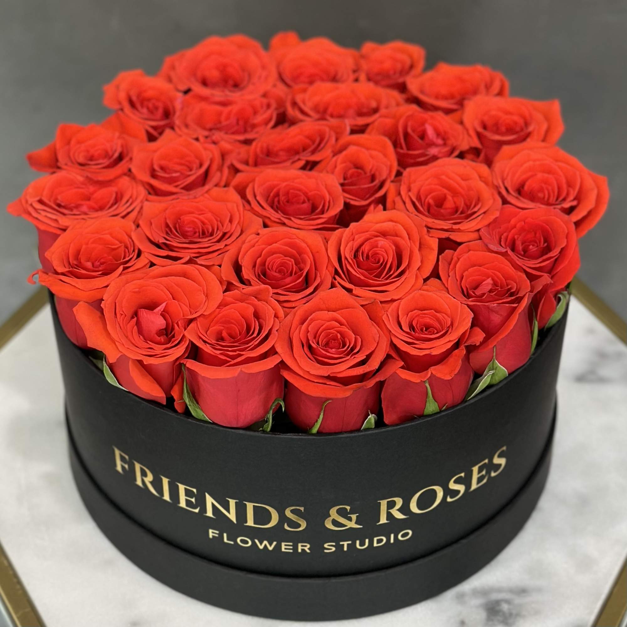 Round box of red roses in a black container